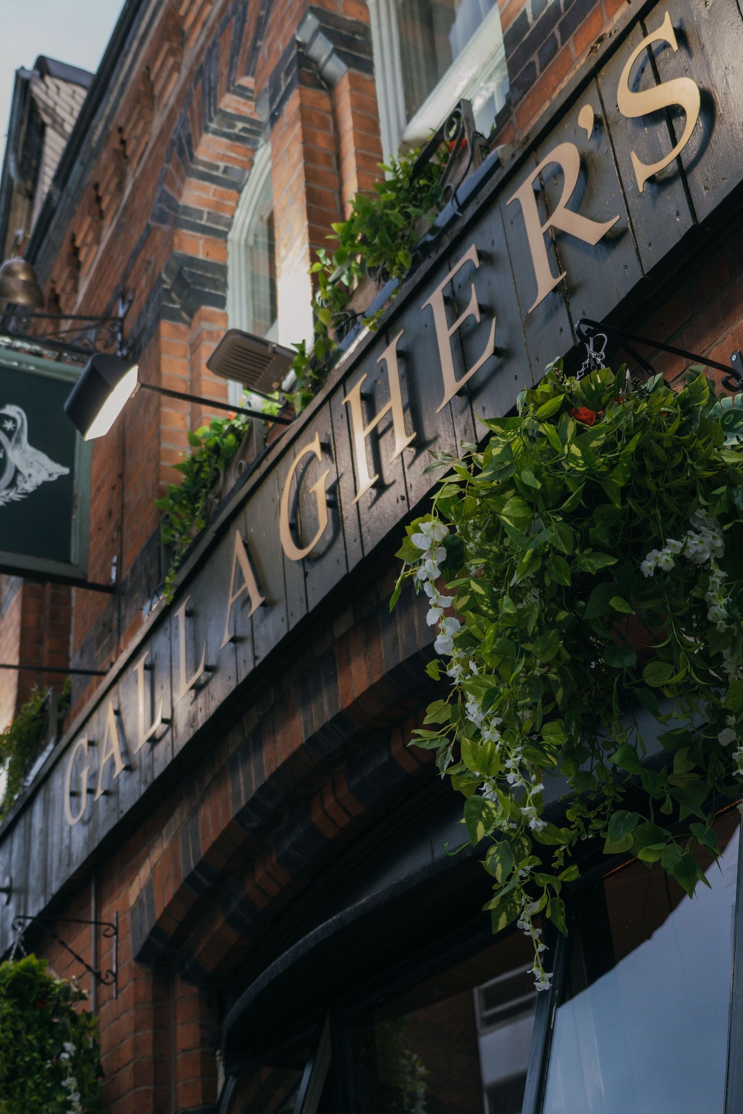 Architectural detail of a historic brick building with decorative signage and green foliage along the facade.