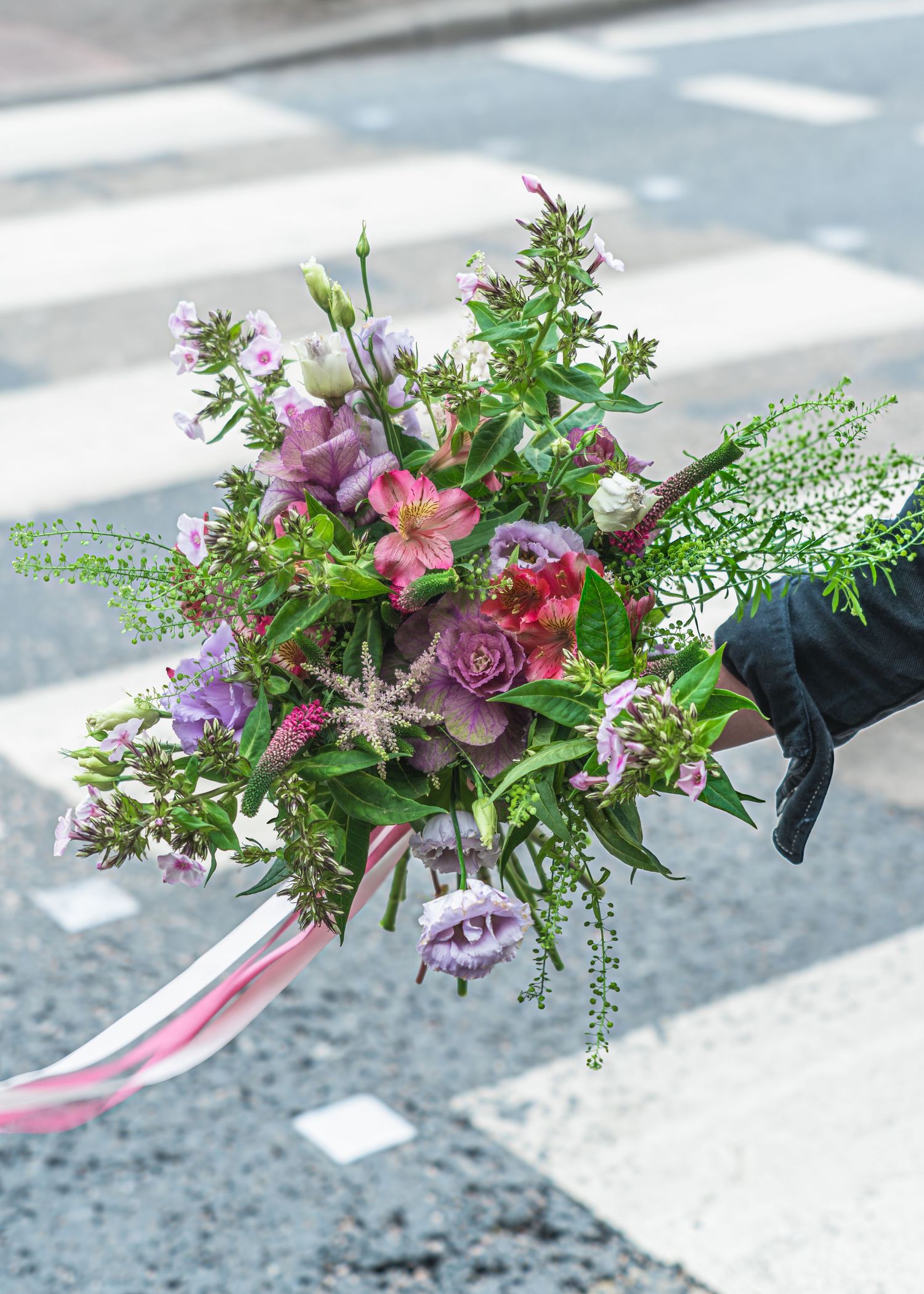Delicate floral bouquets with pink roses and greenery lay scattered on a concrete surface.
