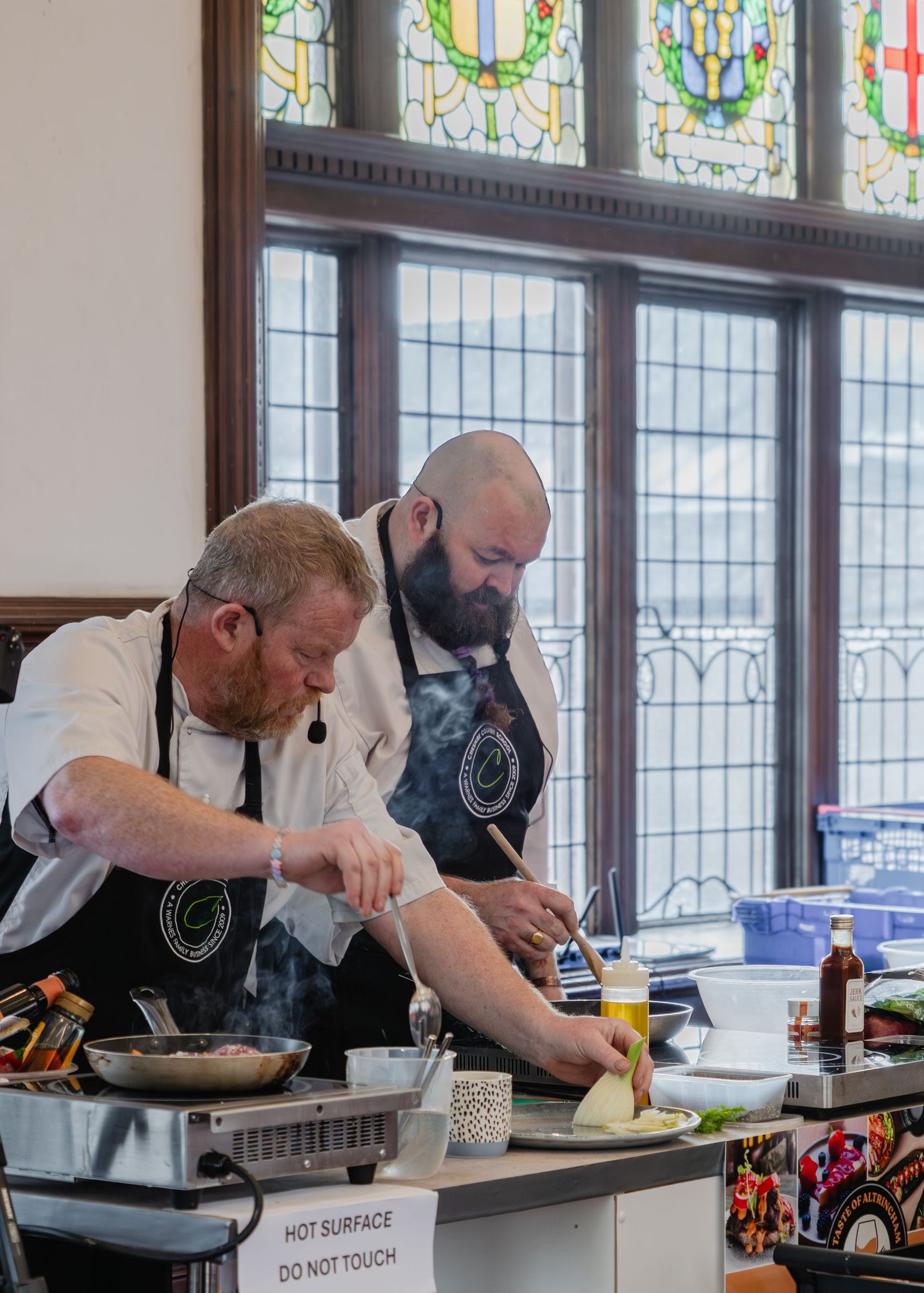 Professional chefs prepare gourmet dishes at cooking stations during a culinary demonstration event.