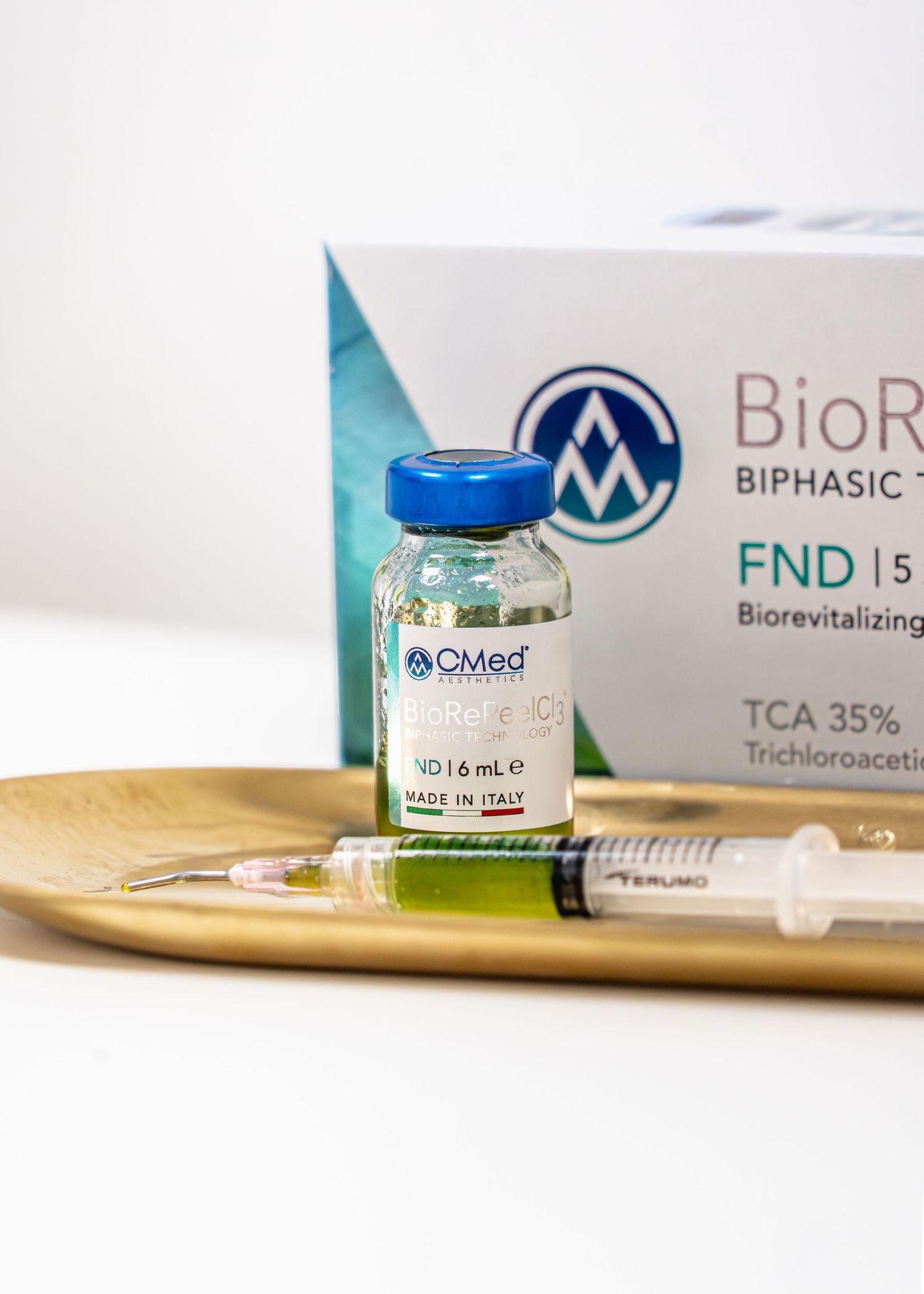 BioRevitalizing biphasic treatment vial with syringe on gold plate, TCA 35% formula made in Italy.