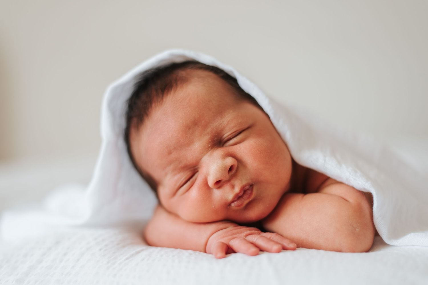 Baby lays head on hands and arms