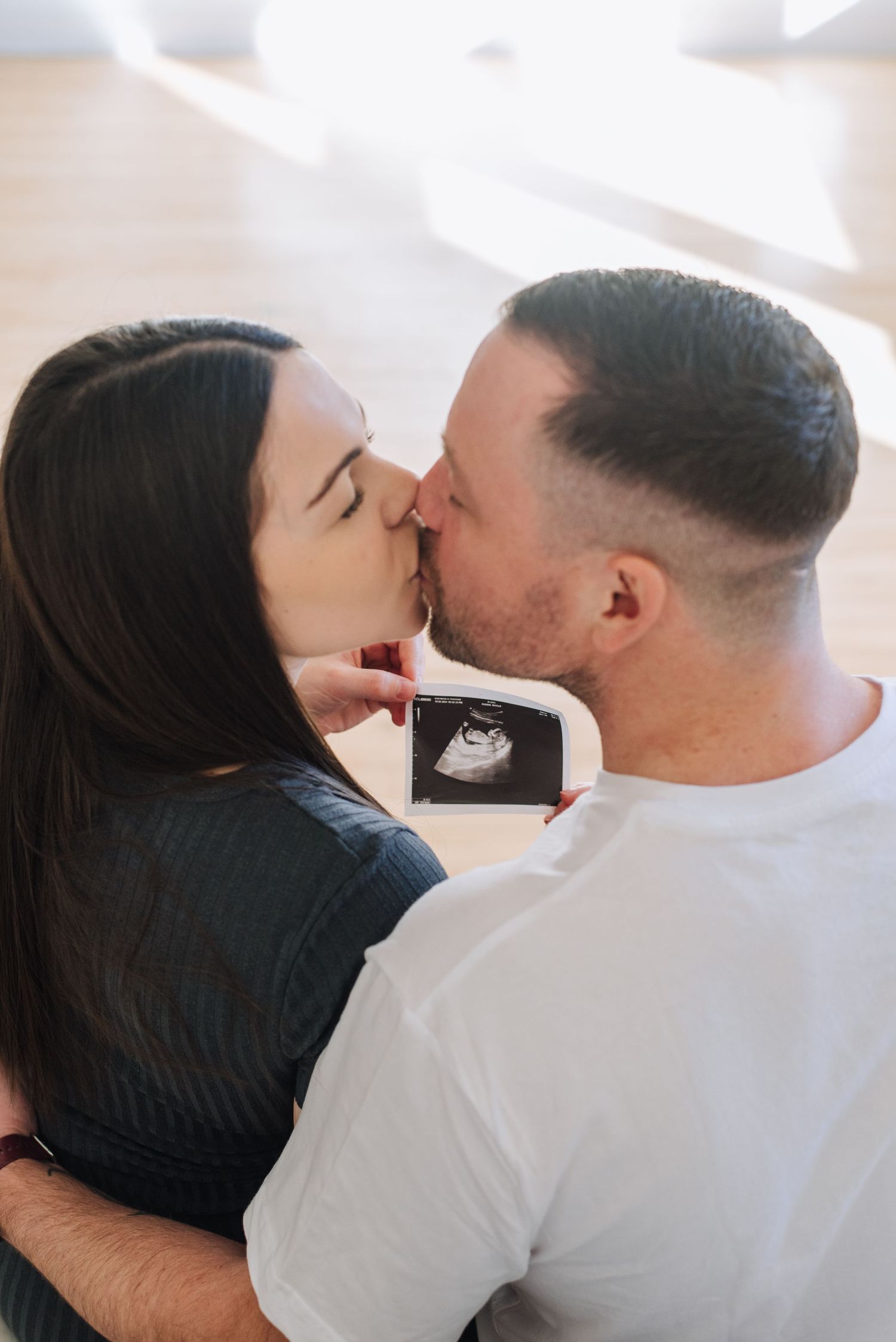 Couple kiss while holding sonogram