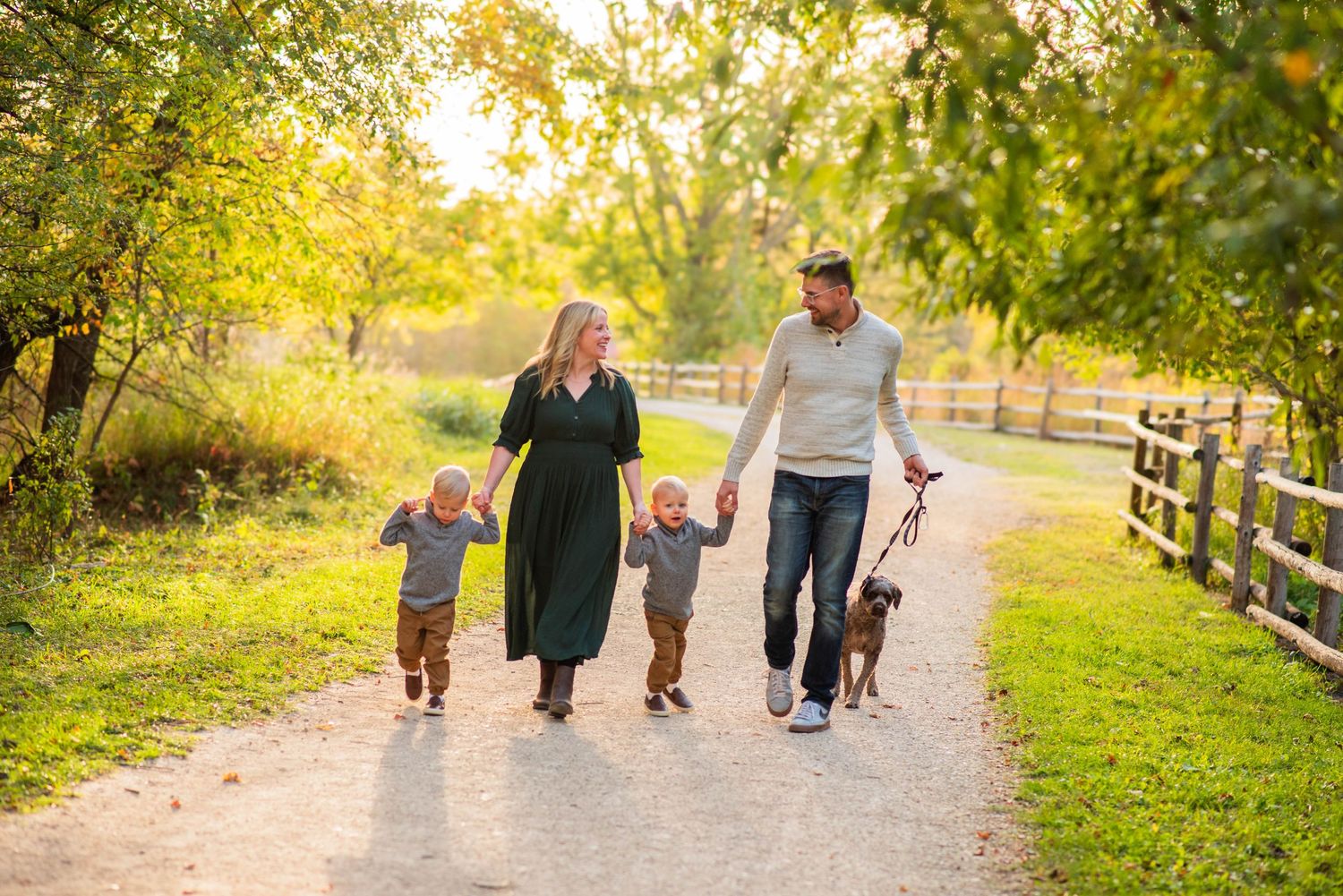 Family walks in park furing fall in winnipeg with their dog during photoshoot
