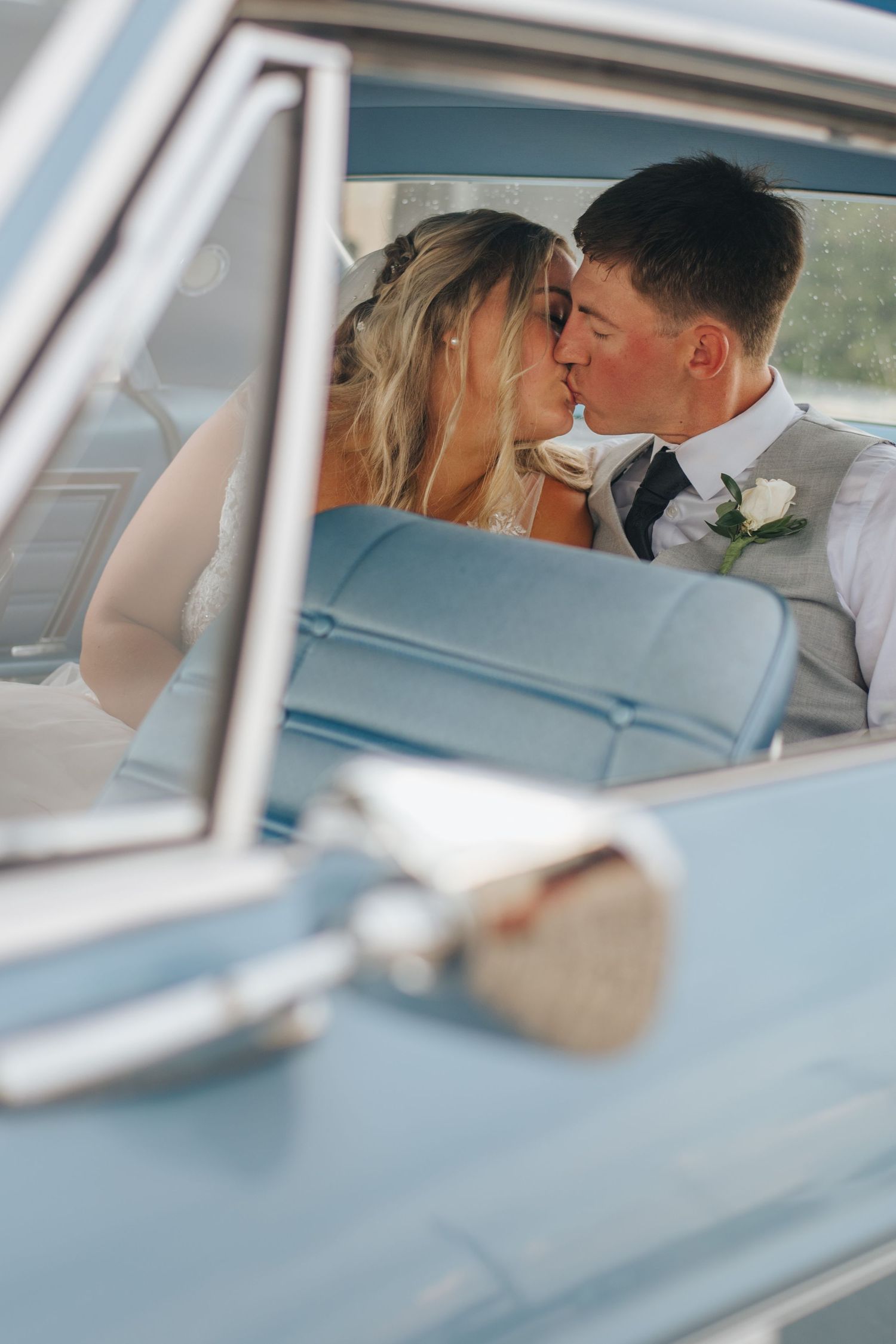 couple kiss in back seat of old car on wedding day