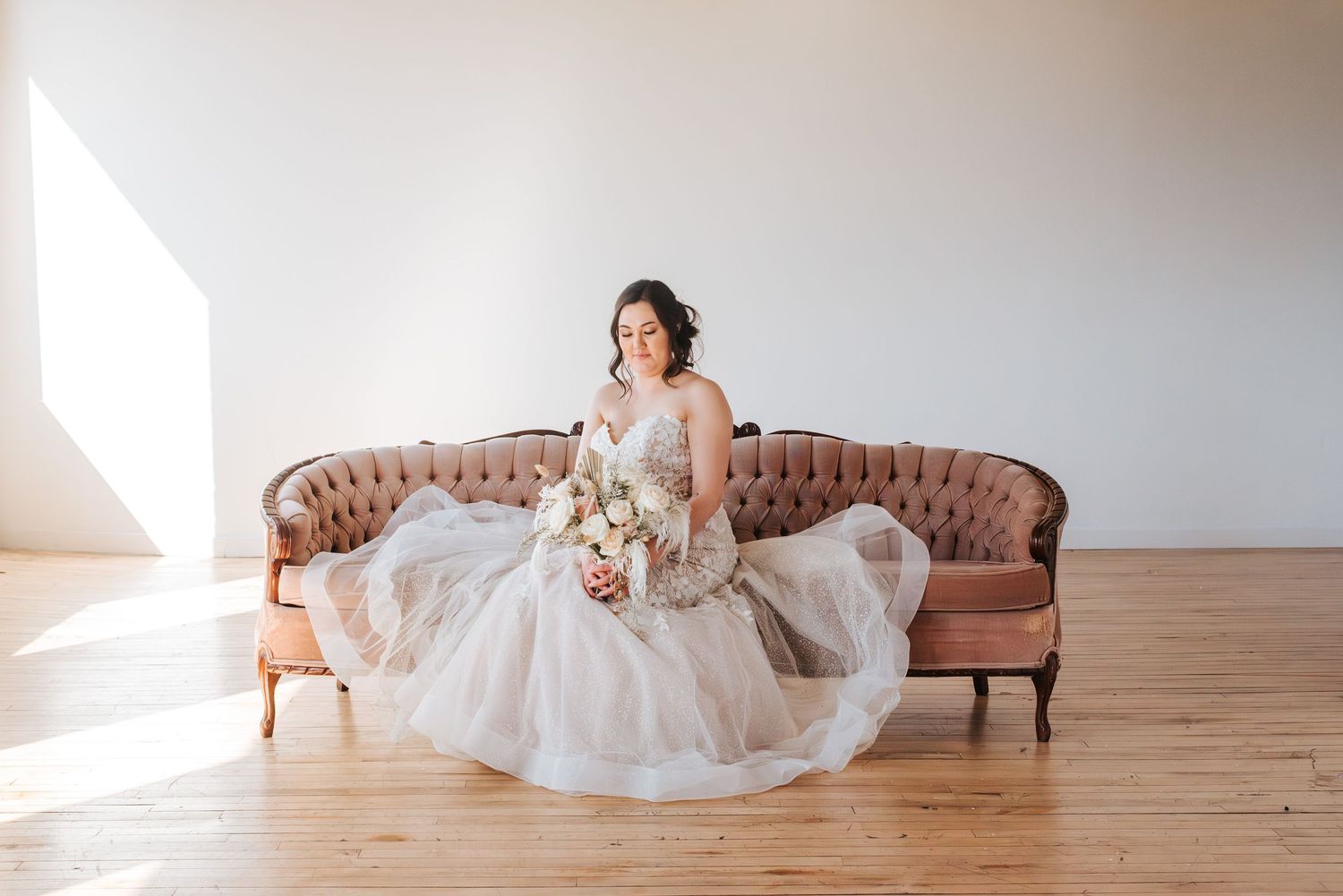 bride looks down at wedding bouquet on antuiqe chair