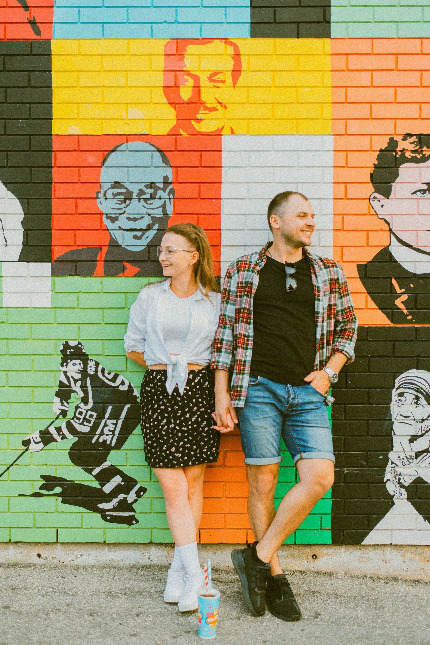 Couple lean against brightly painted wall