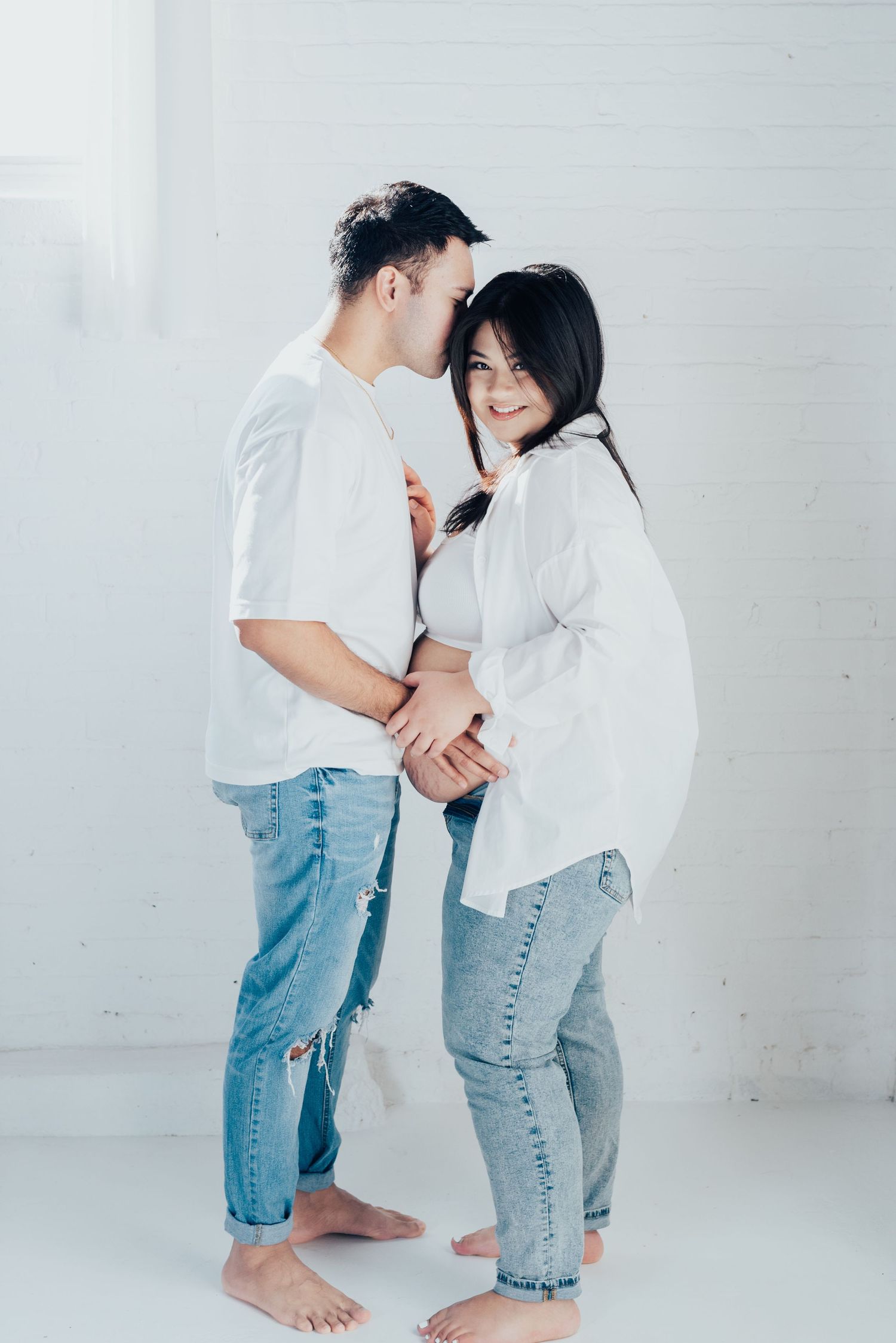 man embraces pregnant wife from behind
