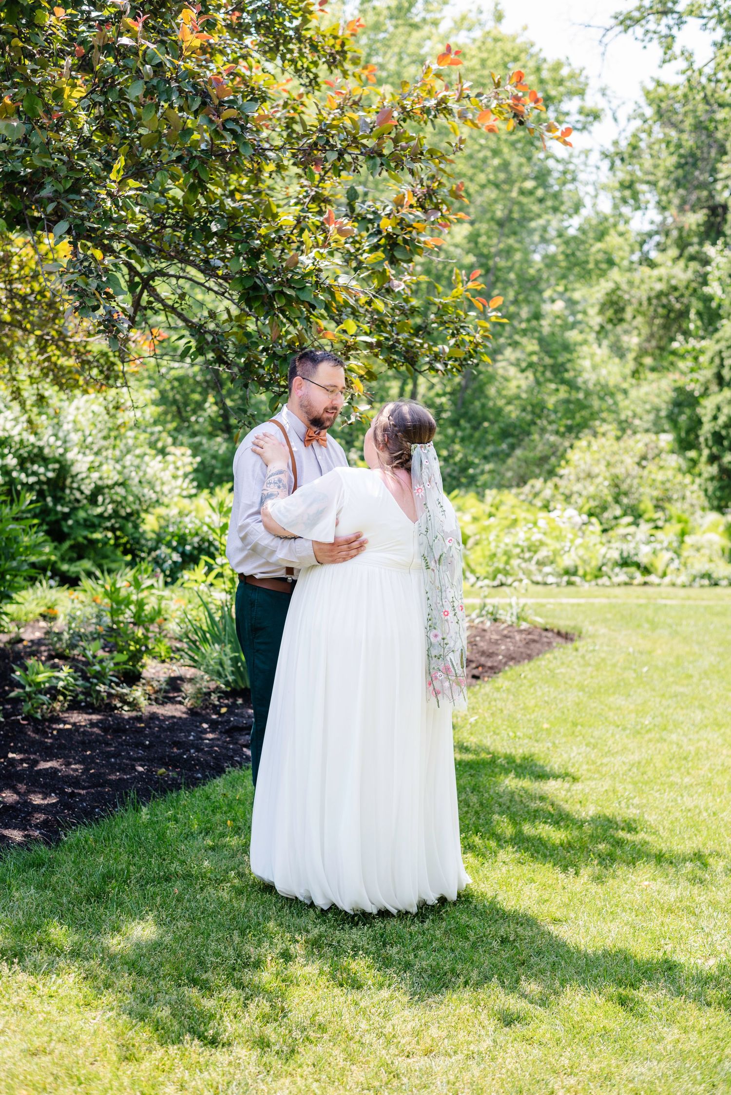 bride and groom dance under a tree in park