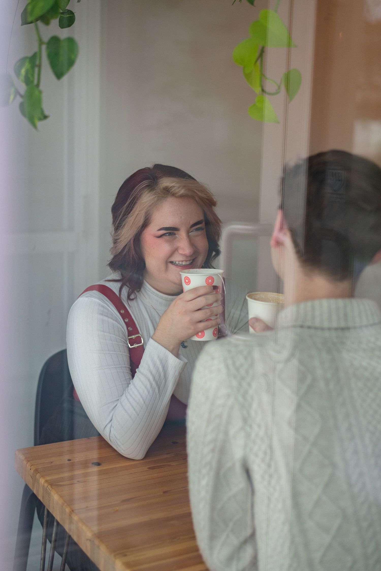 Couple smiles over coffee at winnipeg coffee shop during photoshoot