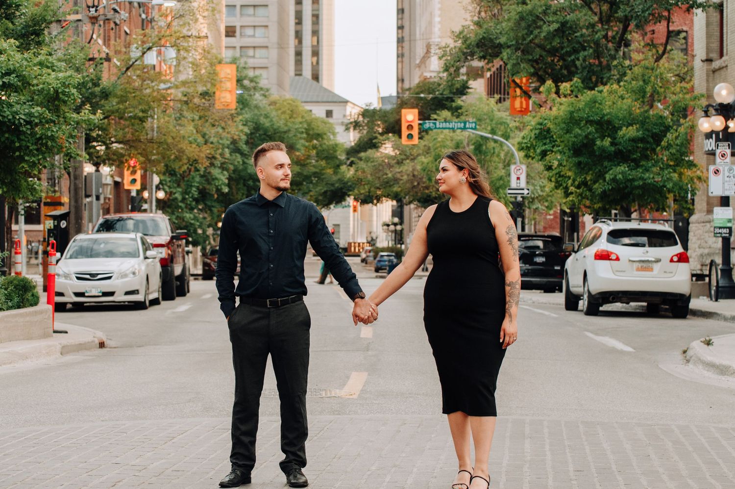 Couple hold hands & look at eachother in middle of busy downtown street