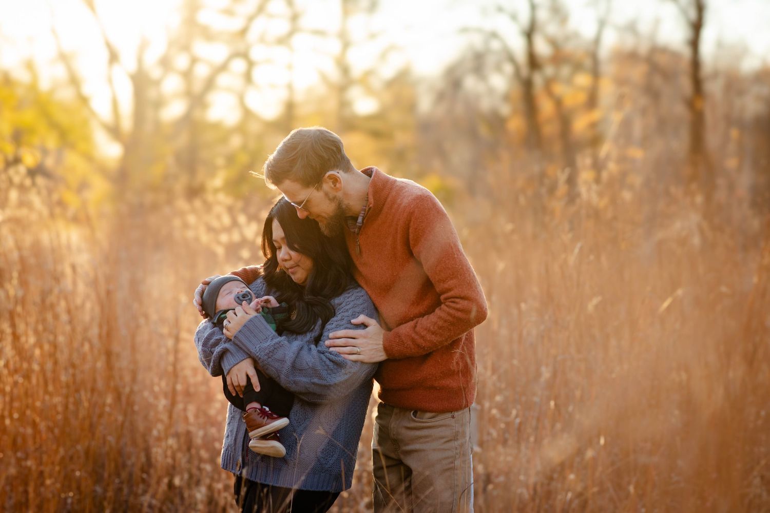 Couple look at baby in grassy feild