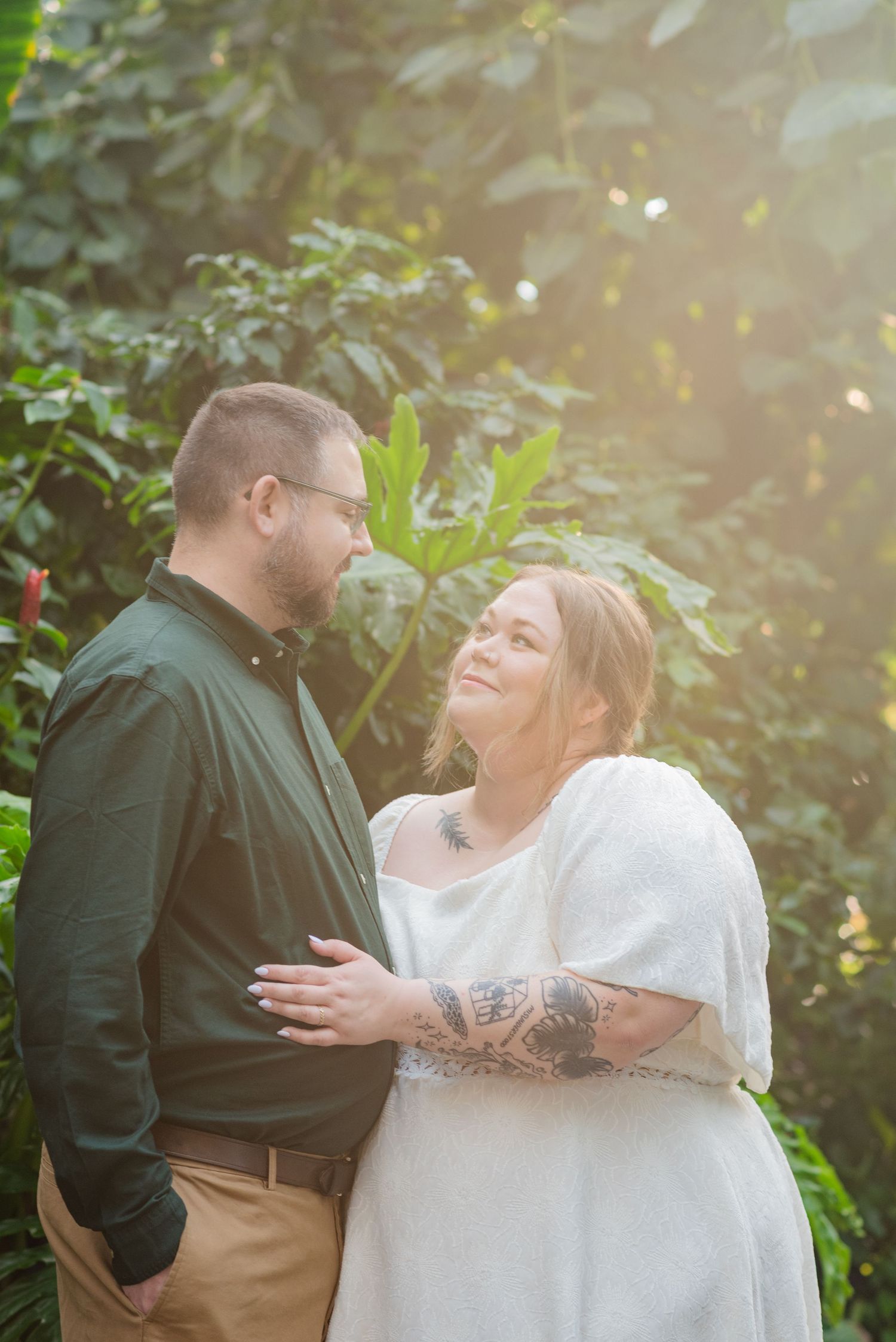 man and woman look at eachother in leafy greenhouse