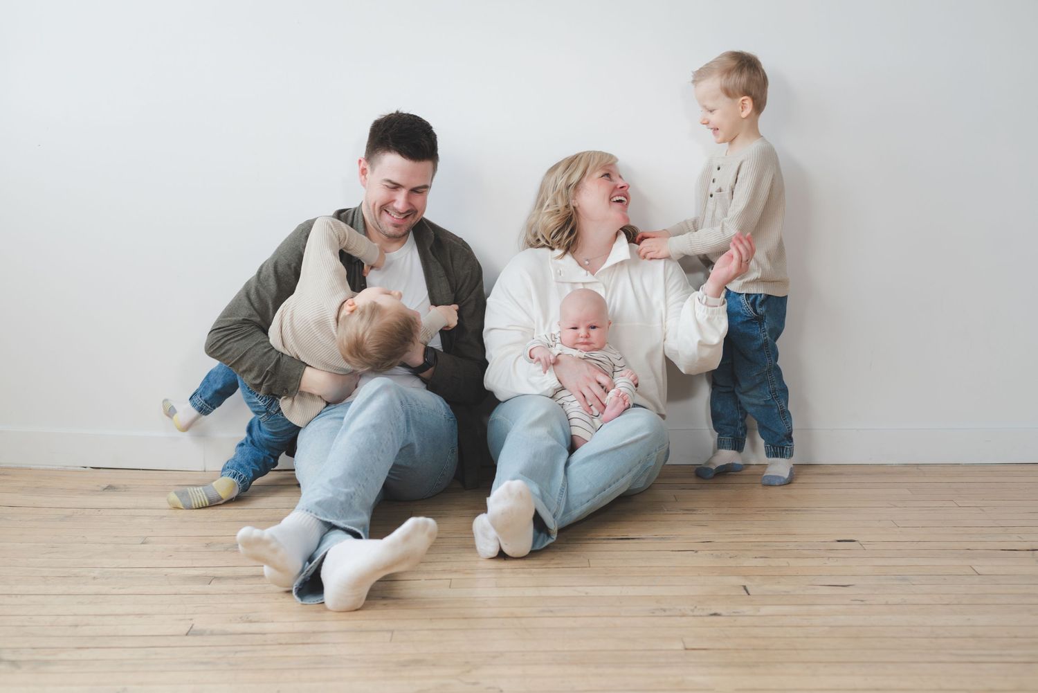Couple laughs and plays with their twin boys and newborn baby