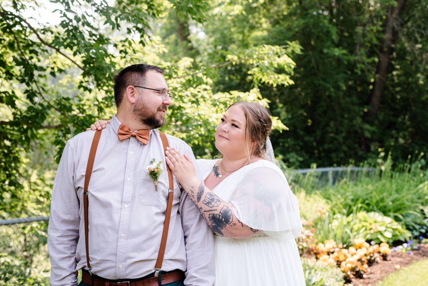Bride and groom look at each other in park