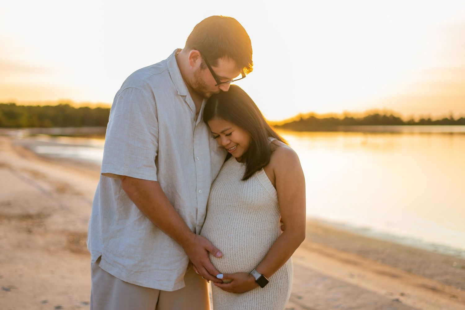 couple kiss and embrace pregnant belly