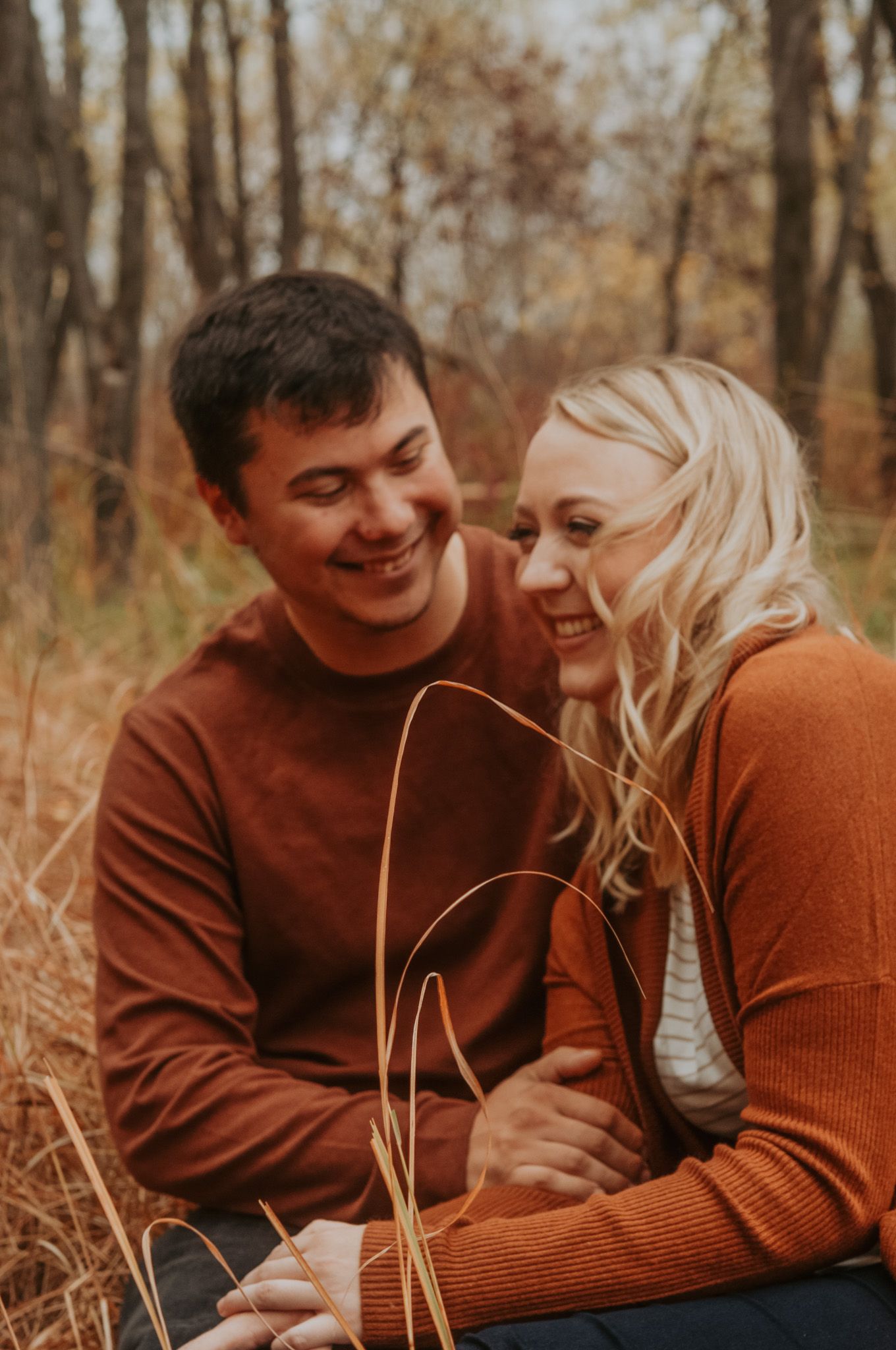 Couple giggles sitting in tall grass