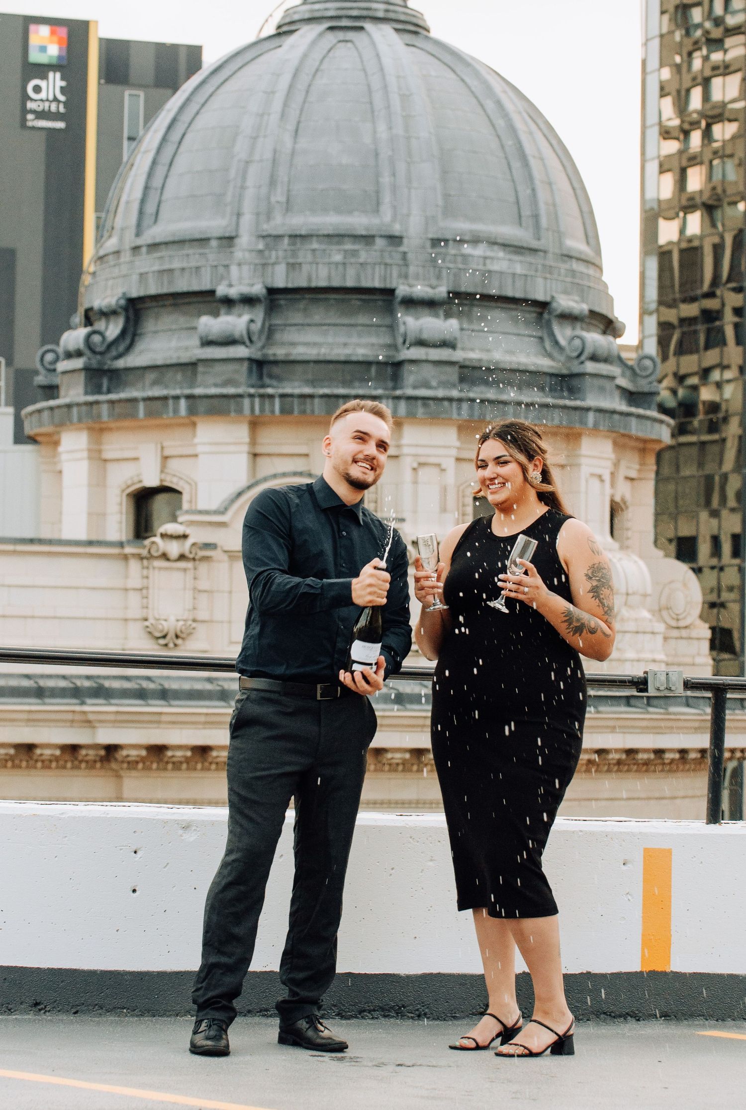 couple pops champange bottle on rooftop