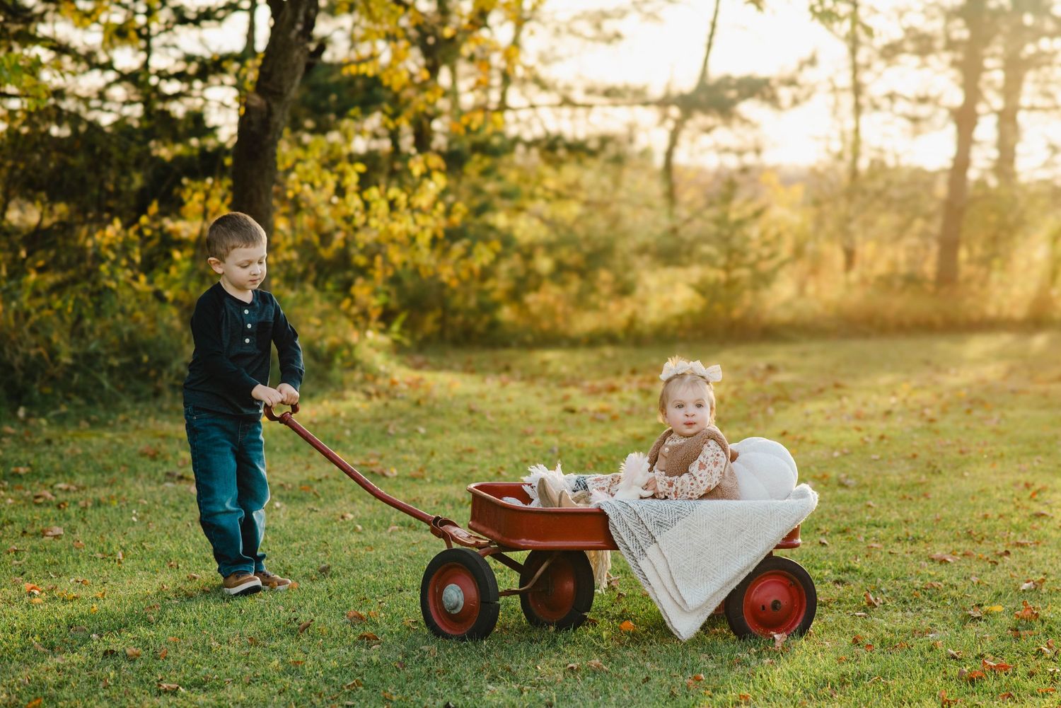 Little boy pulls sister on wagon