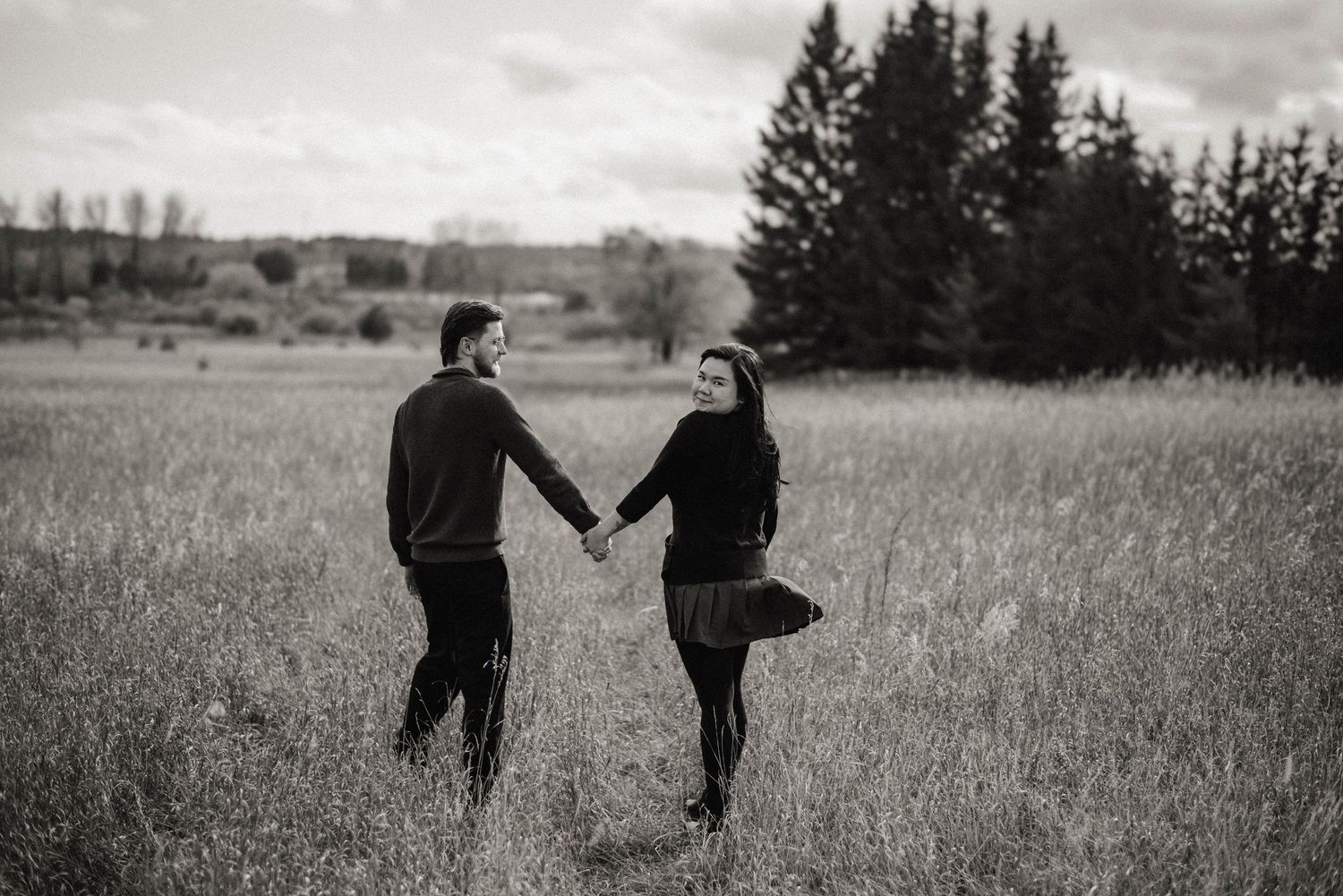 man and woman hold hands in park