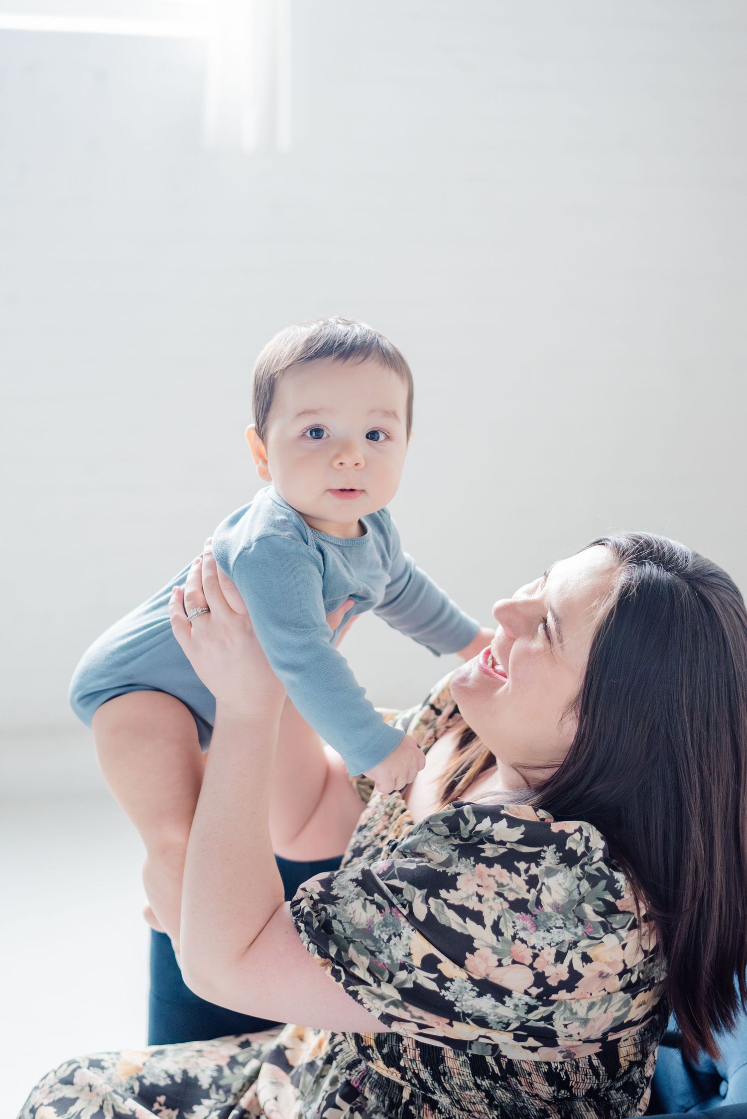 Mom holds baby up to look at the camera