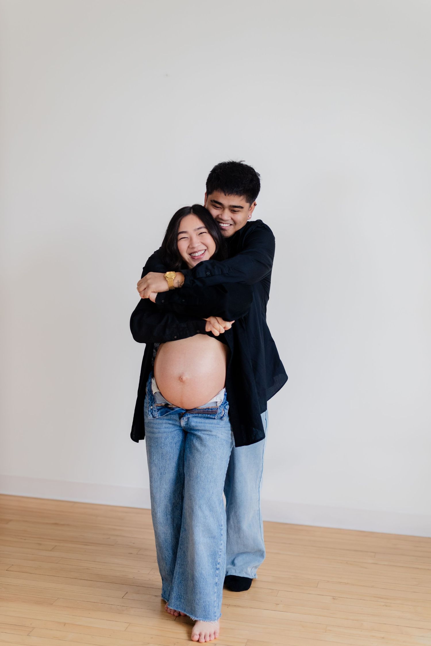 man embraces pregnant wife from behind