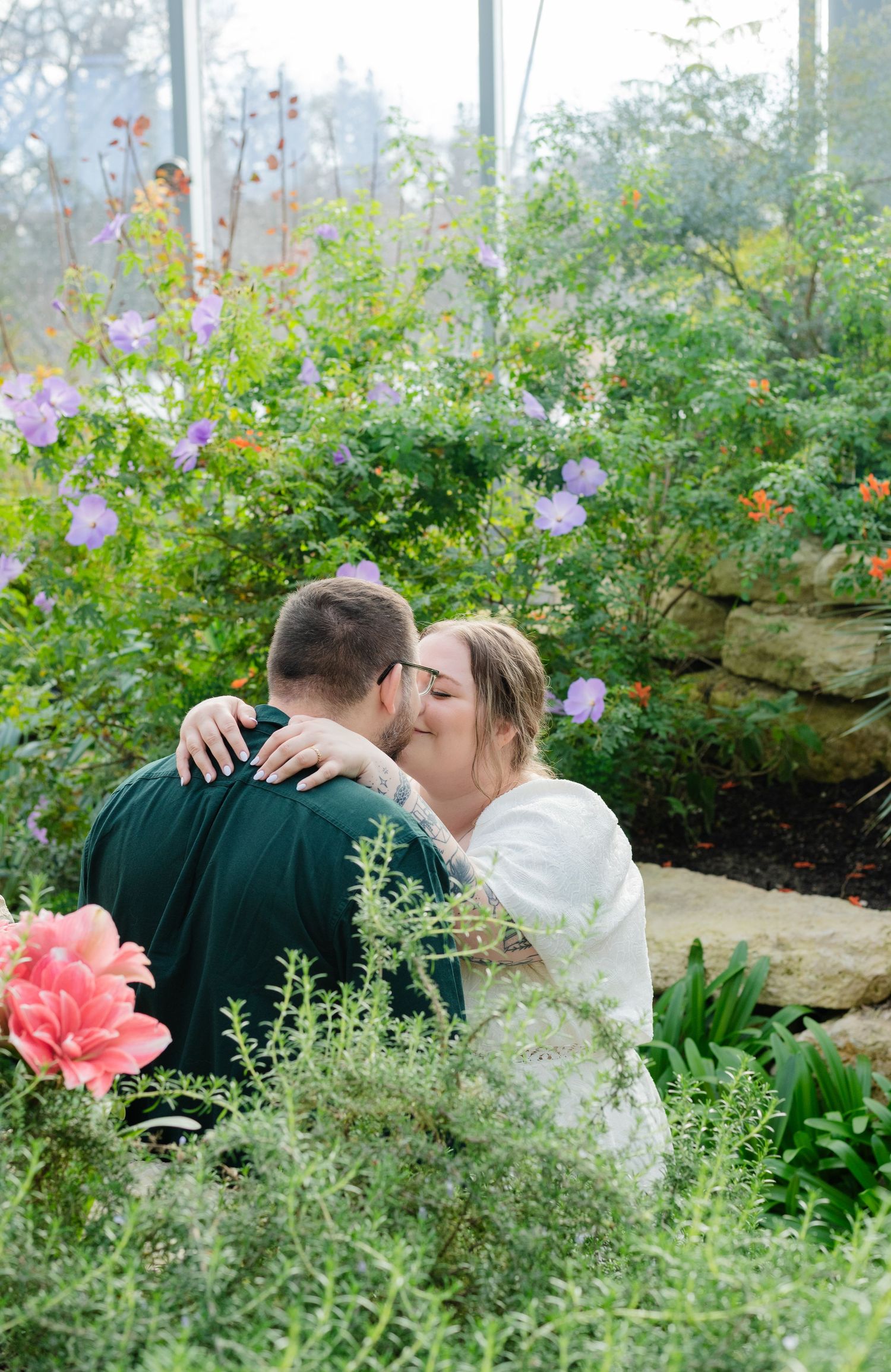 man and woman kiss in leafy greenhouse