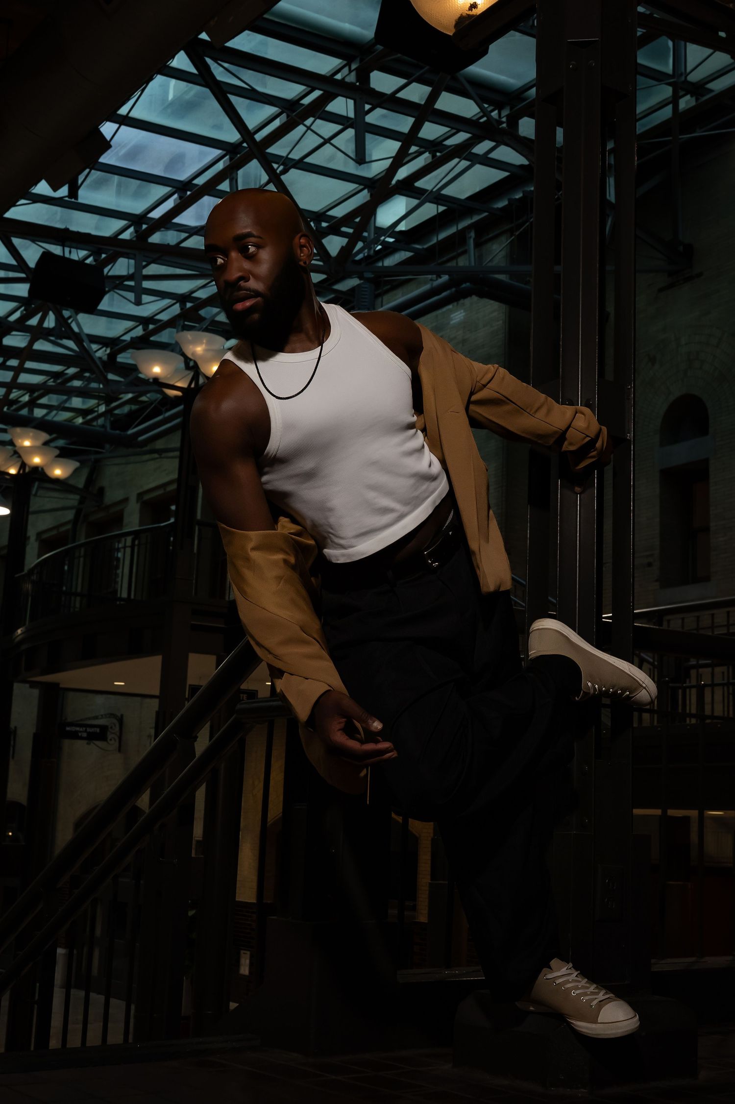 Person in casual attire performing dynamic movements in an industrial space.