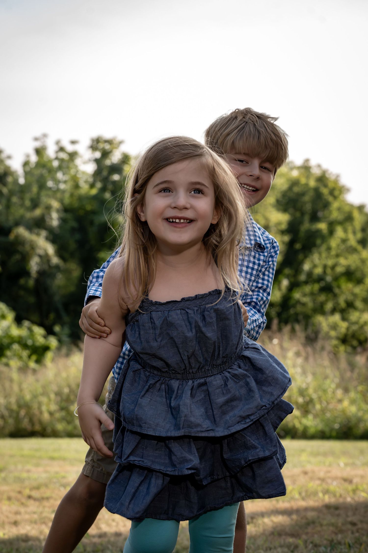 Two children playing and laughing together outdoors in summer.