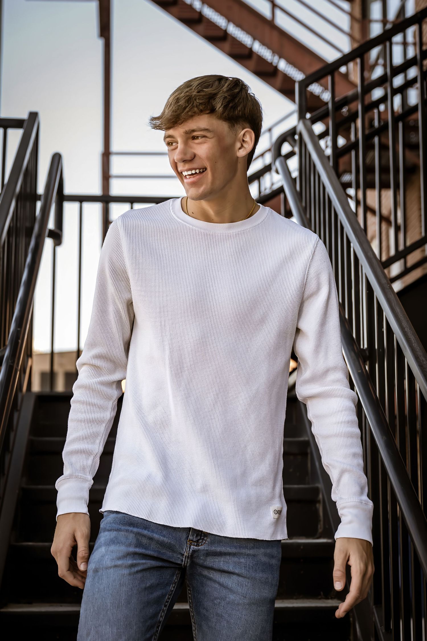 Person in white sweater and jeans posing casually on staircase in sequential shots.