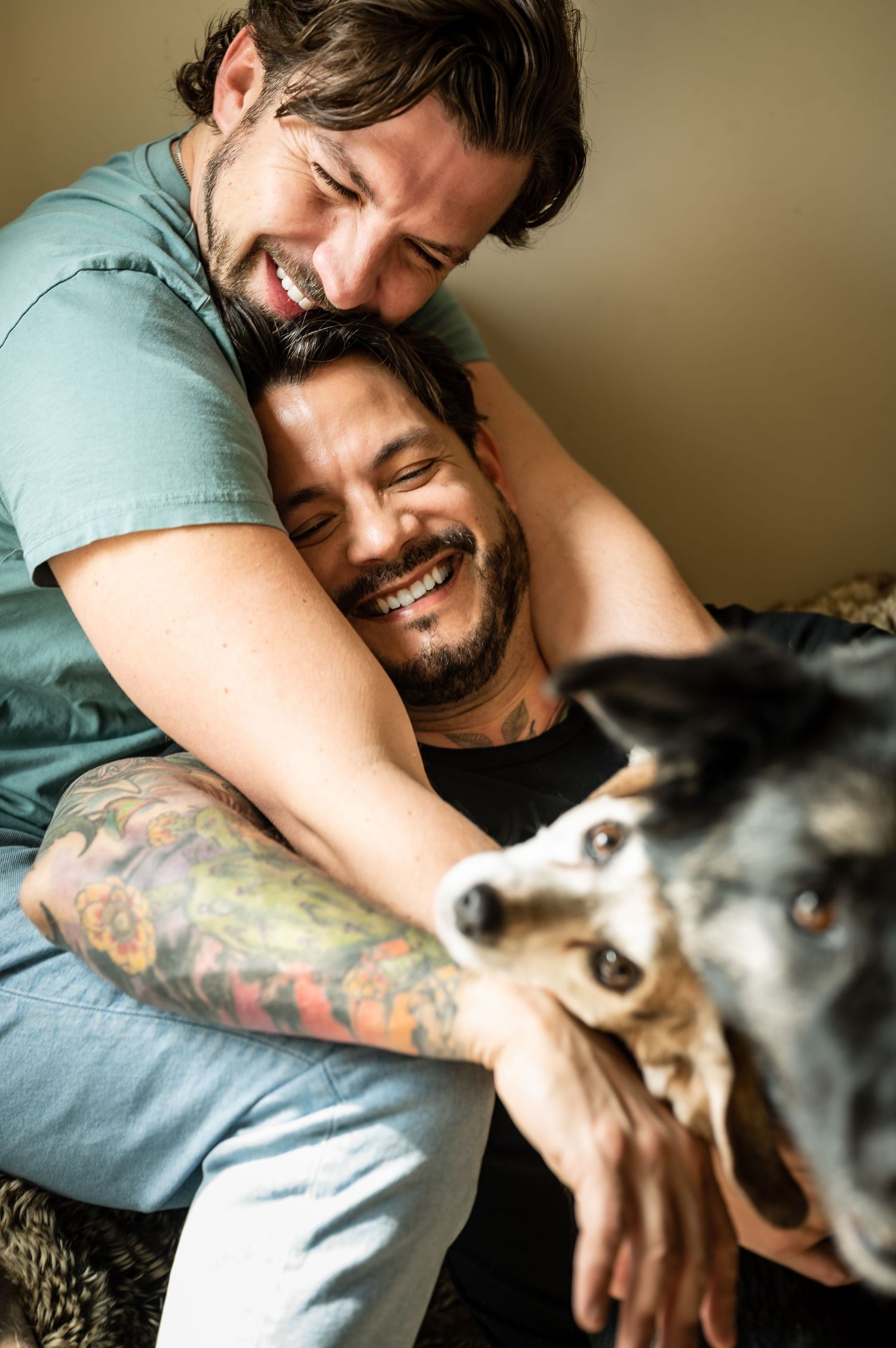 Playful interaction between person in teal shirt and husky dog on couch.
