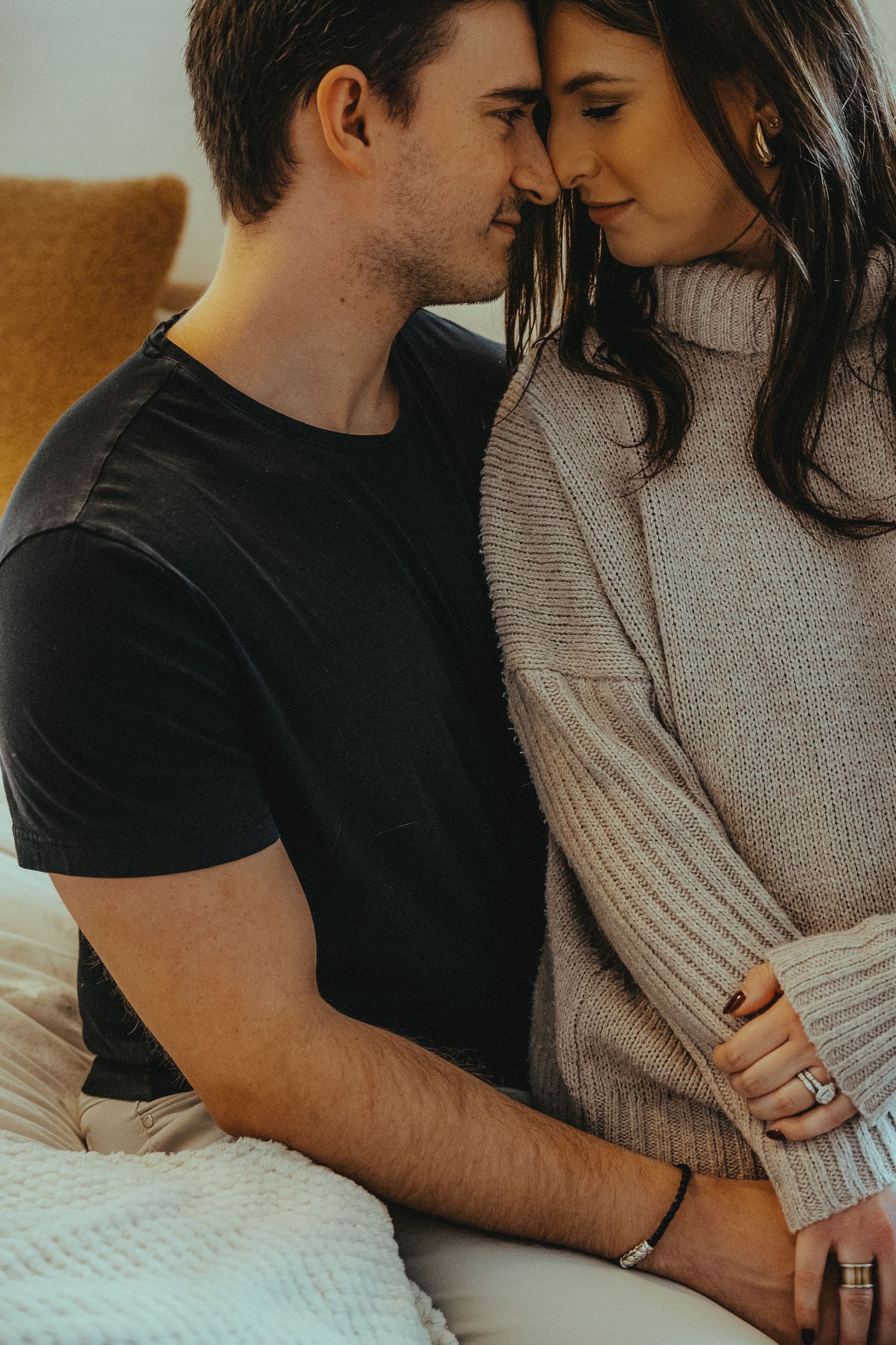 Couple in casual attire sharing tender moments during an indoor photoshoot.