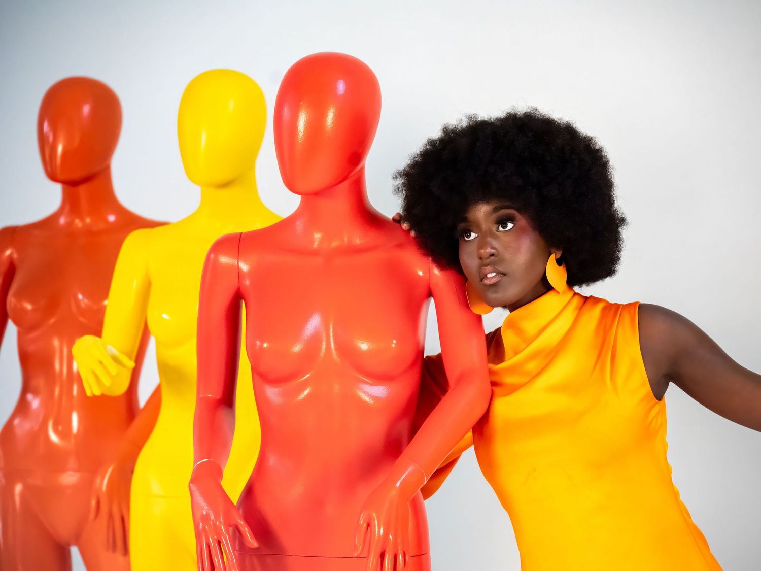 Group of figures painted in bright orange, red and yellow colors posing artistically.