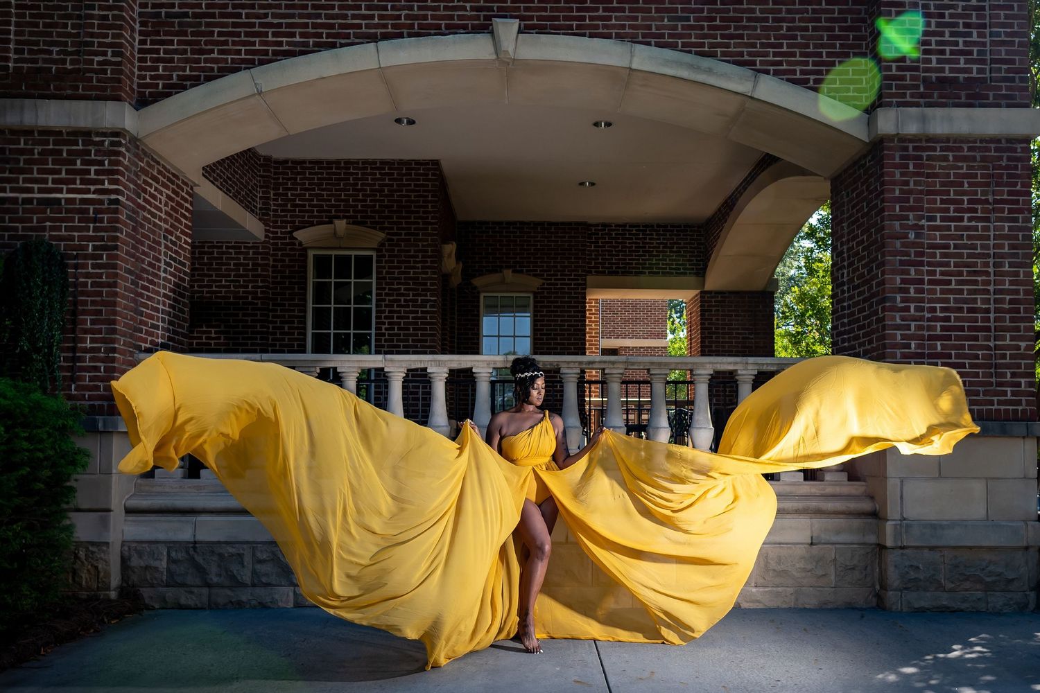 A yellow fabric banner installation flows between brick buildings on a college campus walkway.