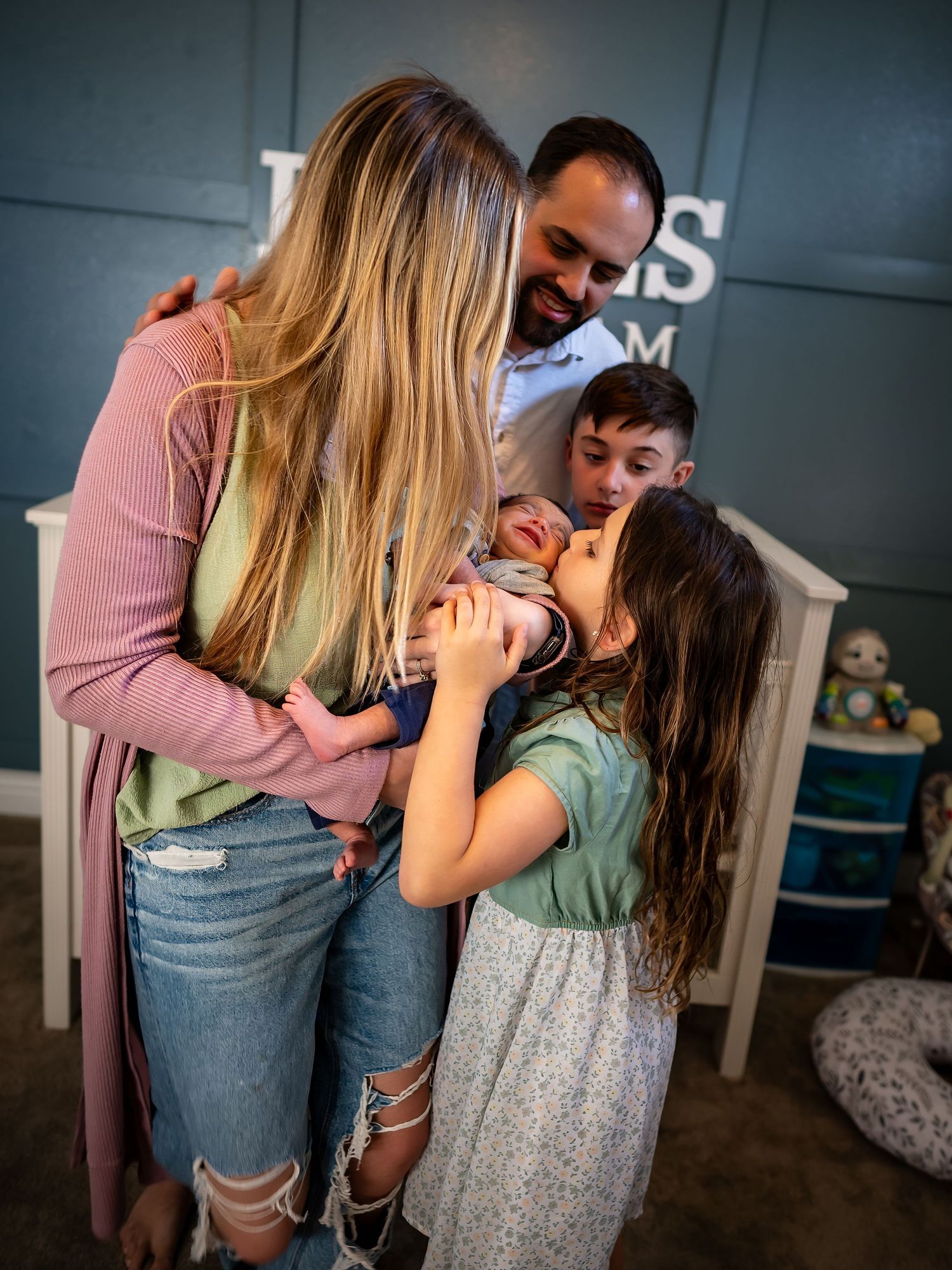 Candid family moment showing affectionate interaction in front of grey wall.