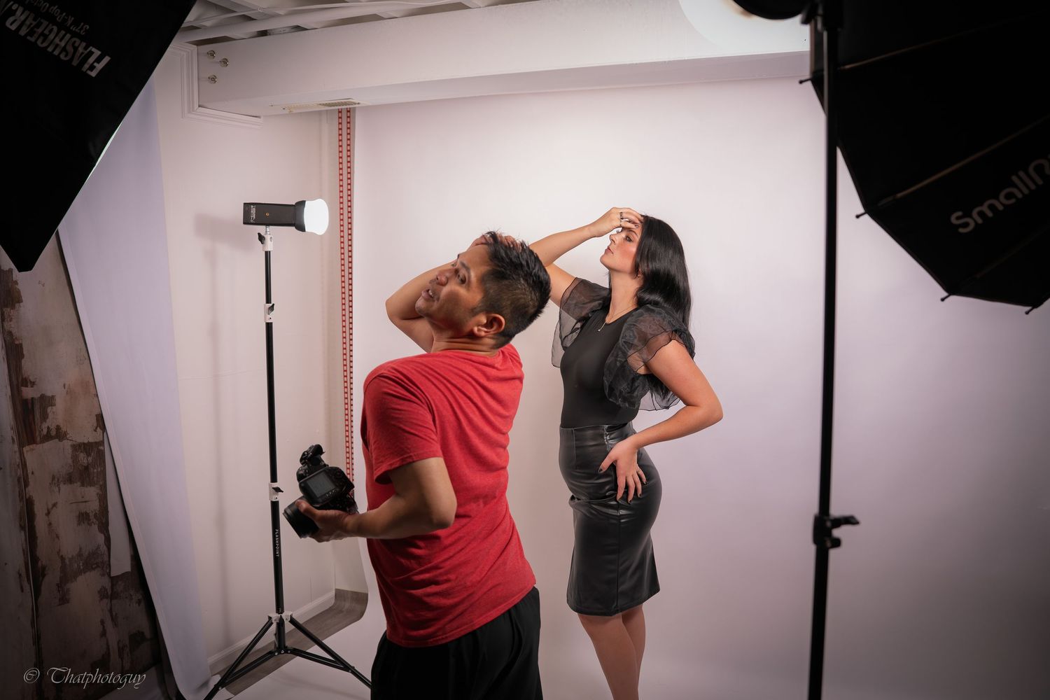 Photographer directing a female model in a professional photo studio with softbox lighting equipment.