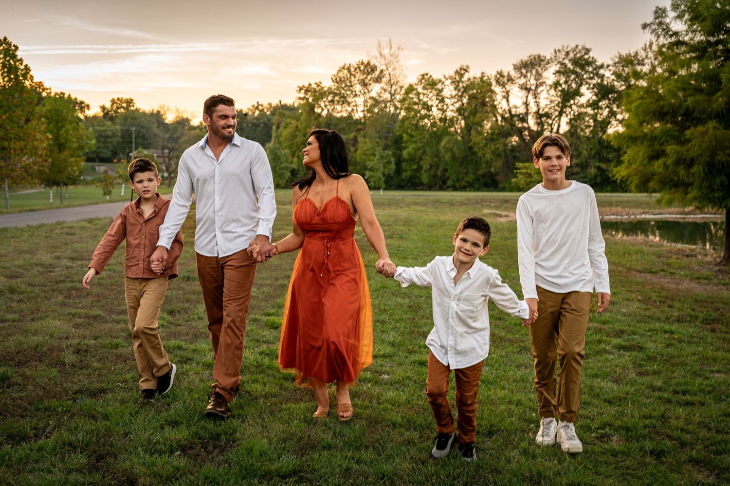 A family walking together in a grassy field during golden hour photography session.