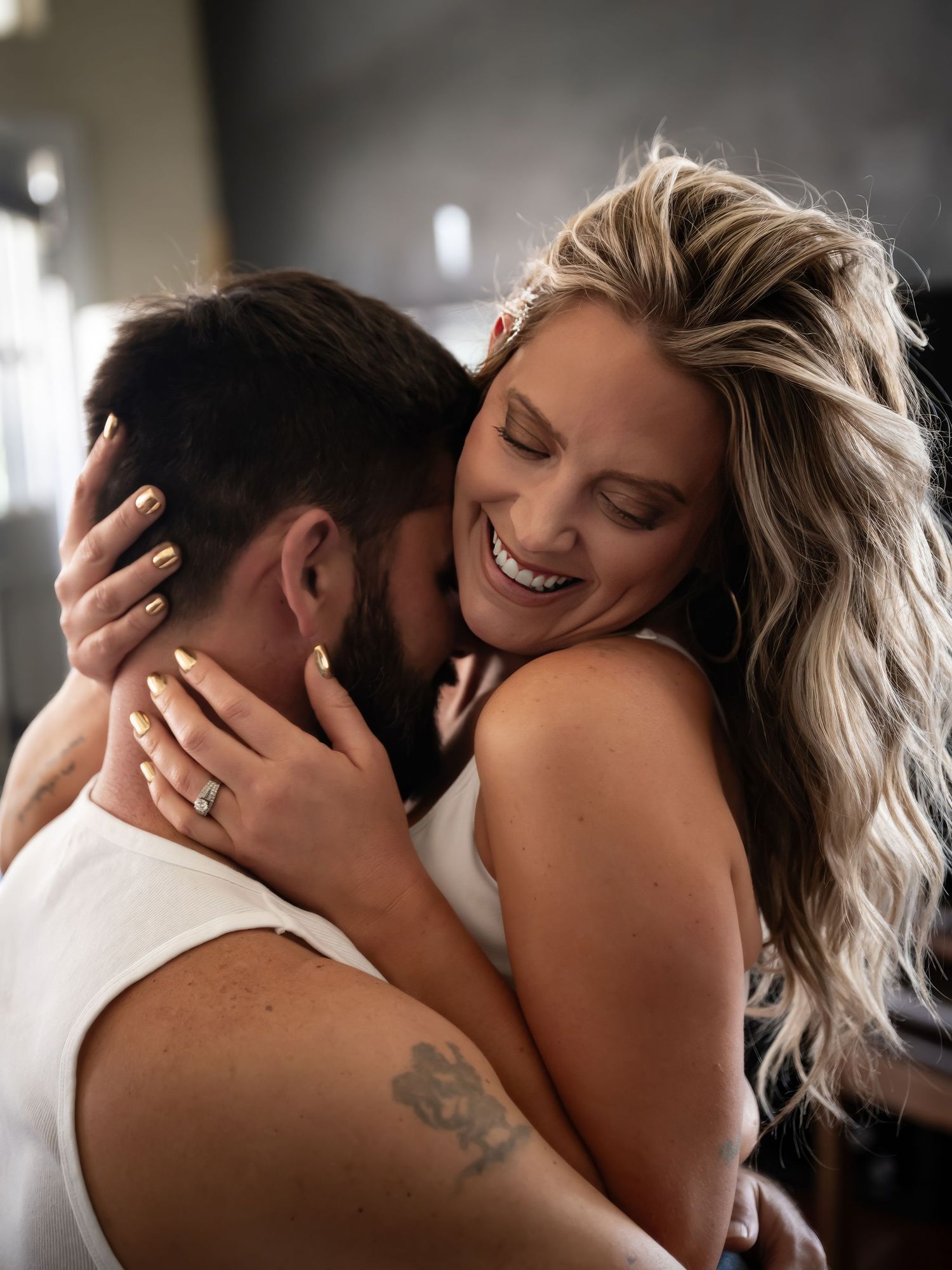 A romantic couple embraces intimately in black and white lighting creating a tender atmospheric moment.