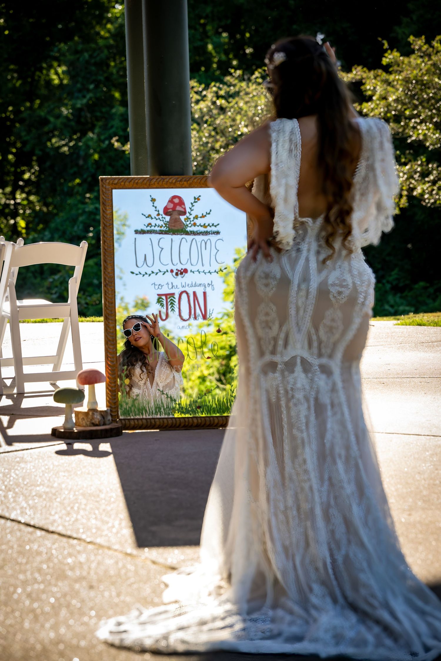 Wedding ceremony setup with lace dress detail and welcome signs in outdoor setting.