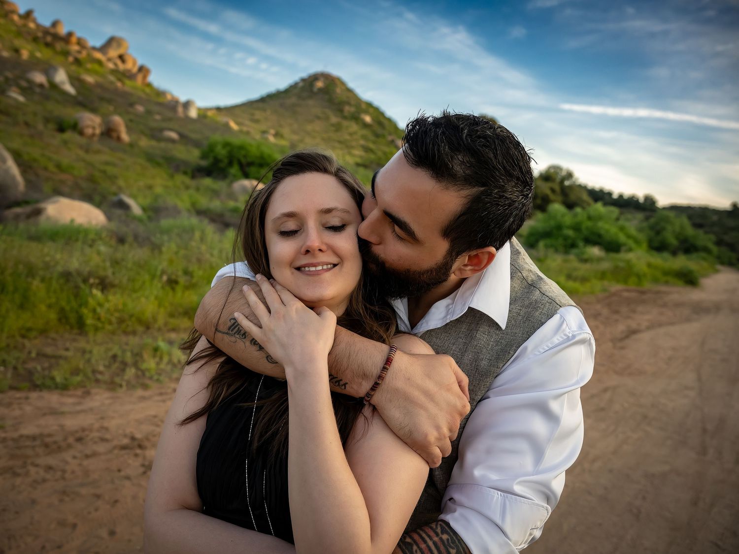 A romantic moment shared between a couple outdoors with mountains in the background.