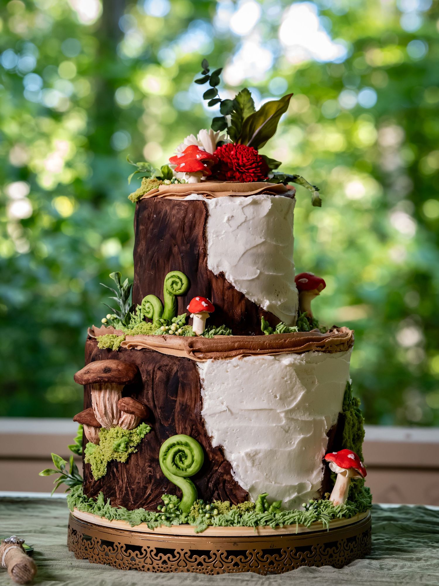 Rustic woodland-themed wedding cake with white frosting, tree bark texture, and green accents.