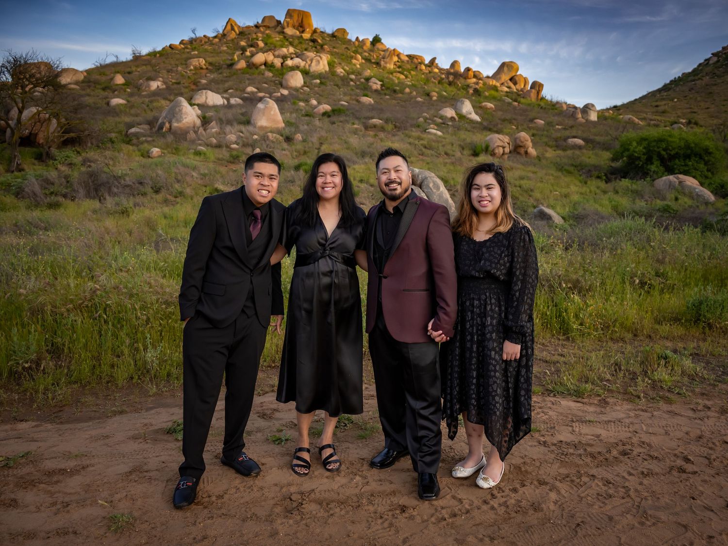 A group walking together on a dirt path with mountains and blue sky in the background.