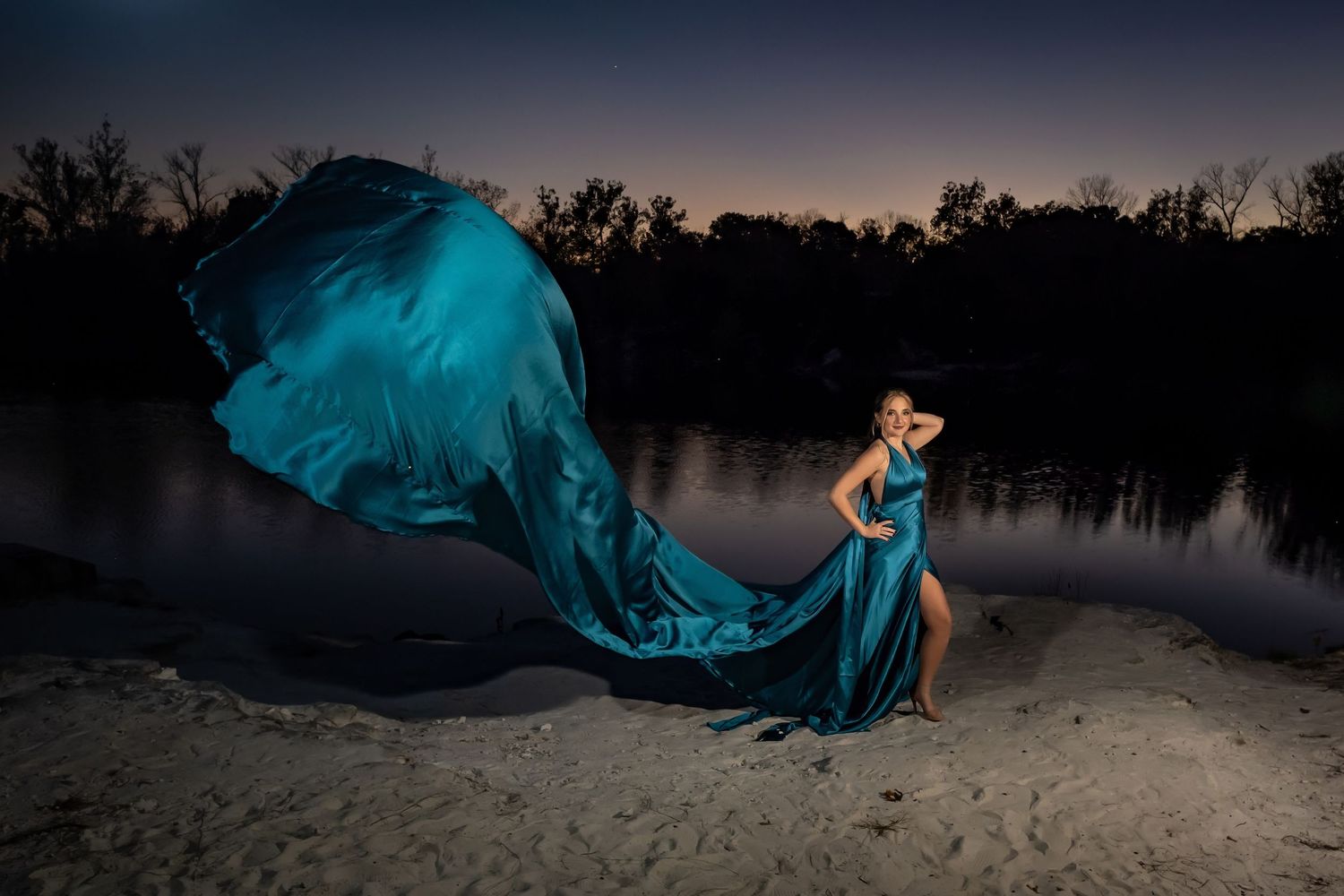 Flowing blue fabric creates dramatic movement against night sky.