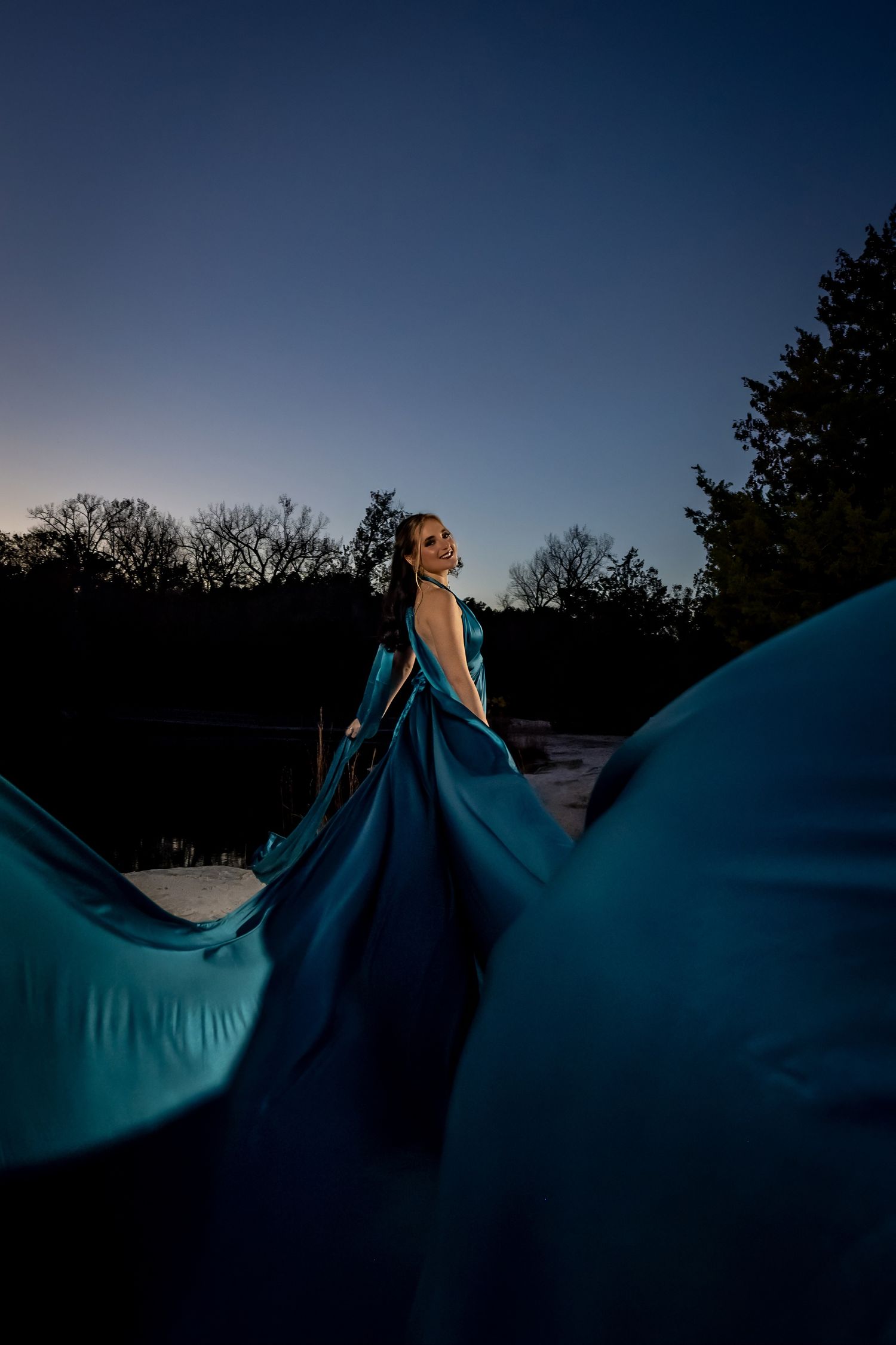 Flowing blue fabric billows dramatically against a dusky evening sky.