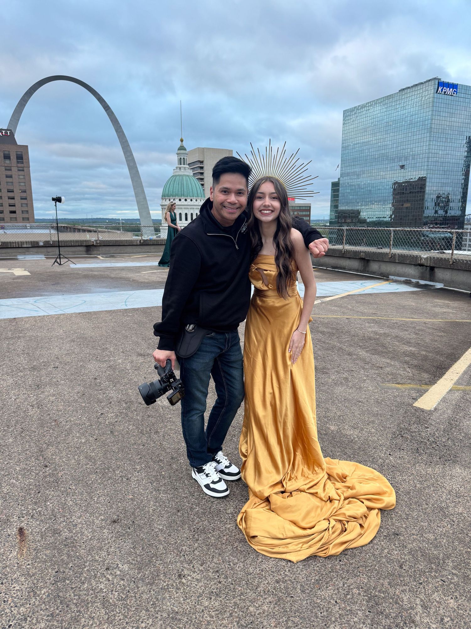 A couple poses together with the iconic Gateway Arch and St. Louis skyline visible in the background.