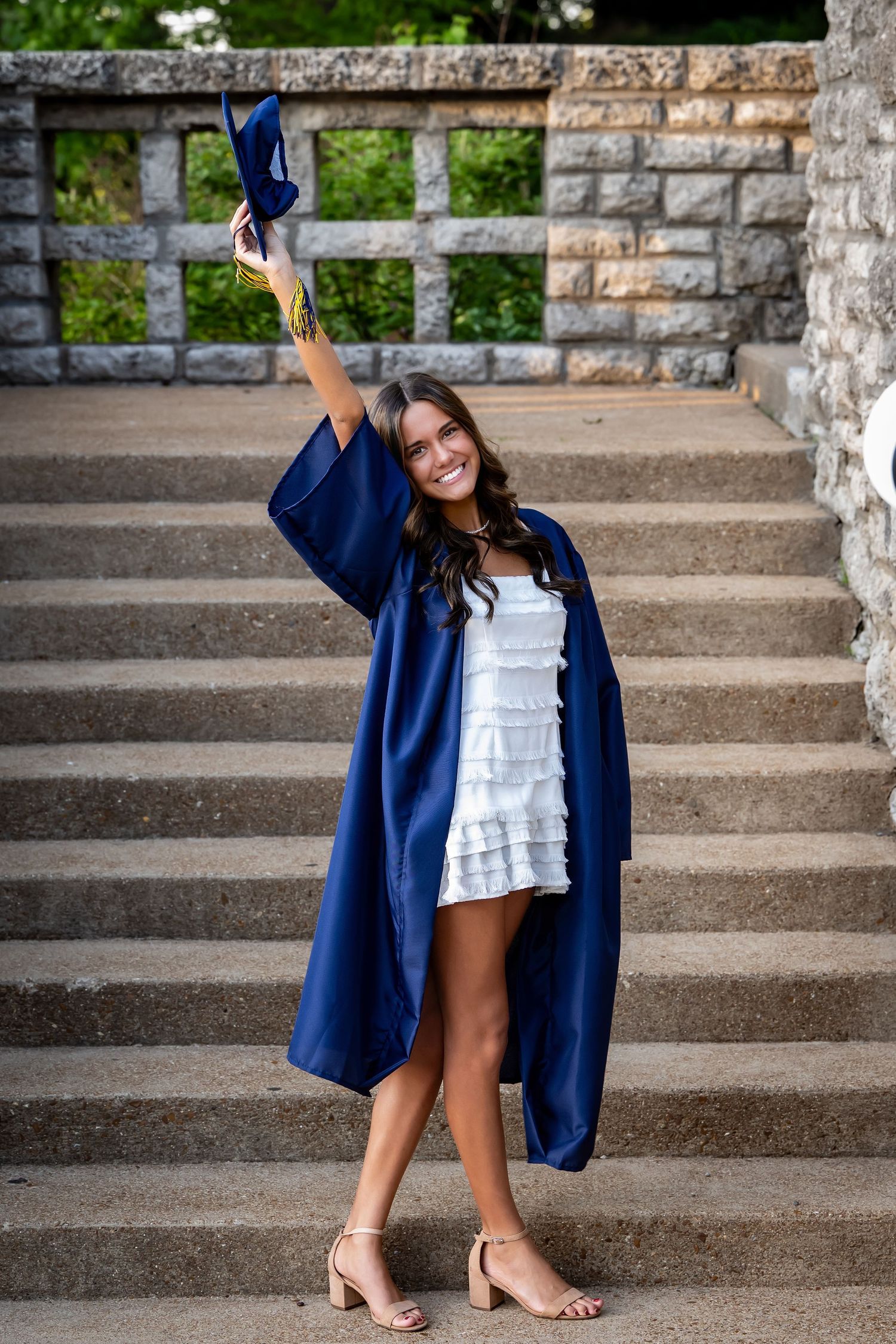 Graduation photos on stone steps featuring a navy blue cap and gown.