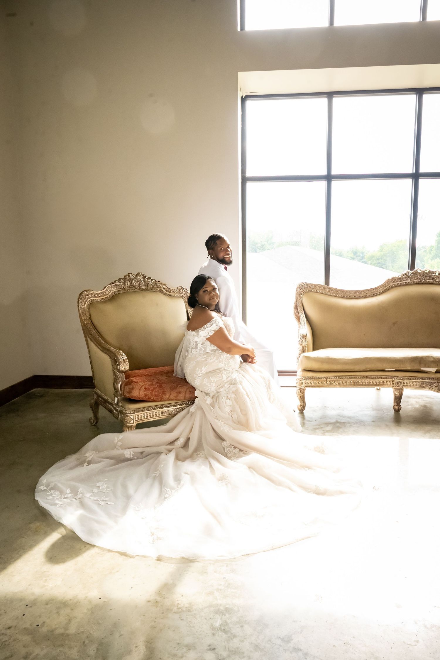 A bride in a white gown twirls gracefully near vintage furniture in natural light.
