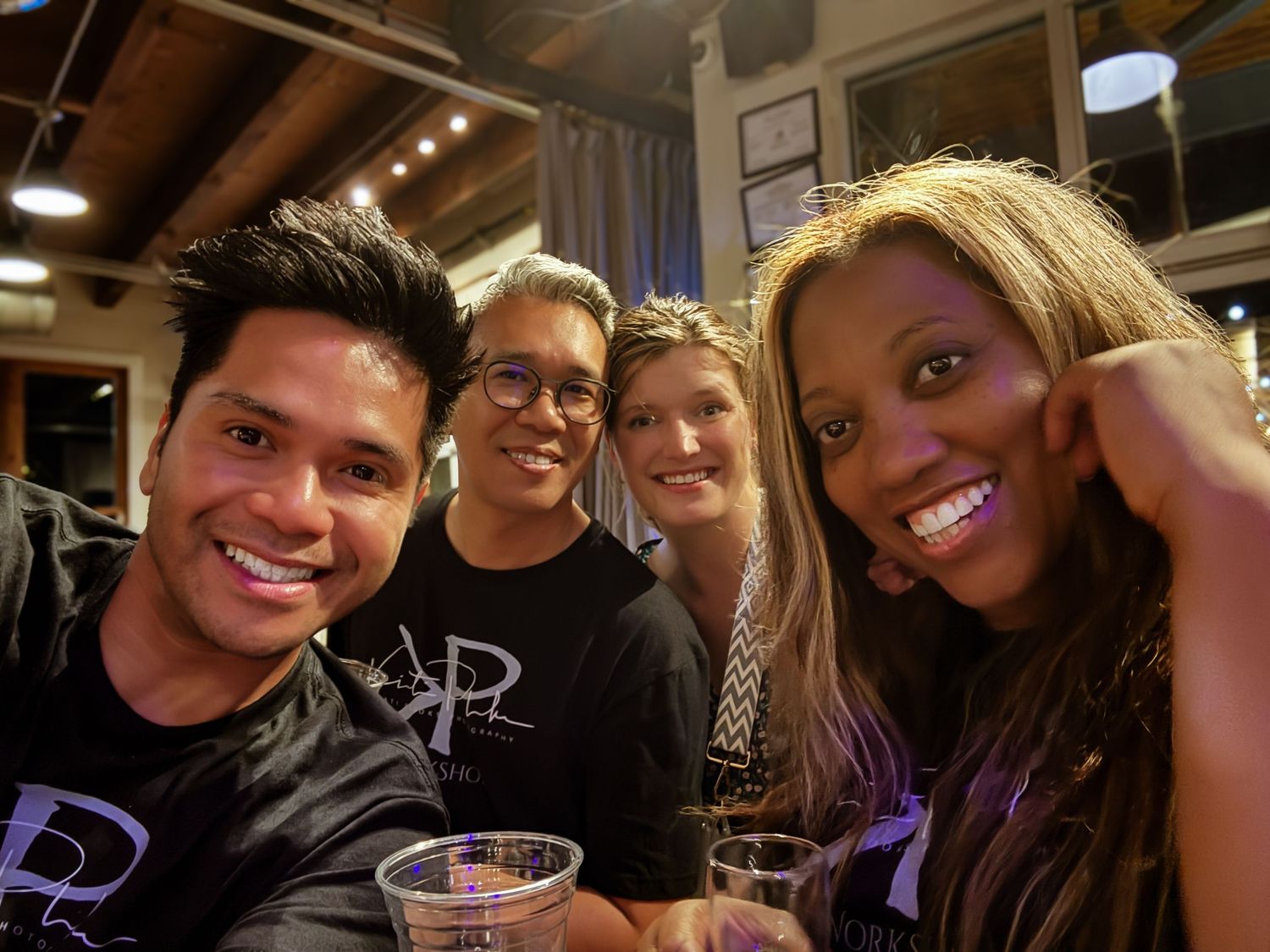 A group of people smile and pose together at what appears to be a restaurant or bar setting.