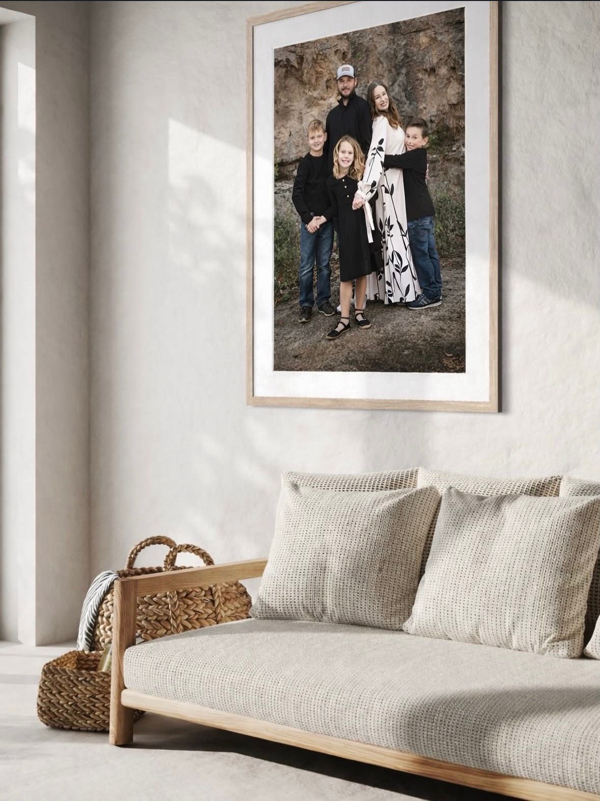 Framed family portrait photo above a neutral linen sofa in a minimalist living room with natural wood accents.