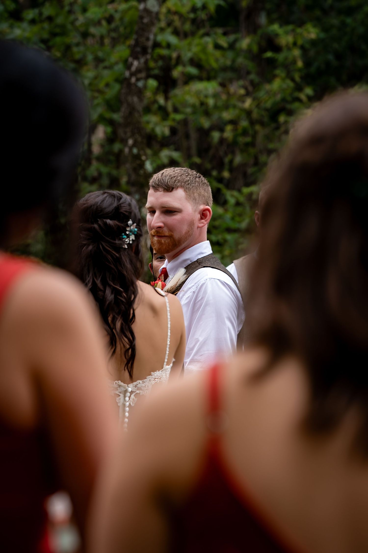 Wedding guests gather outdoors during an intimate ceremony surrounded by greenery.