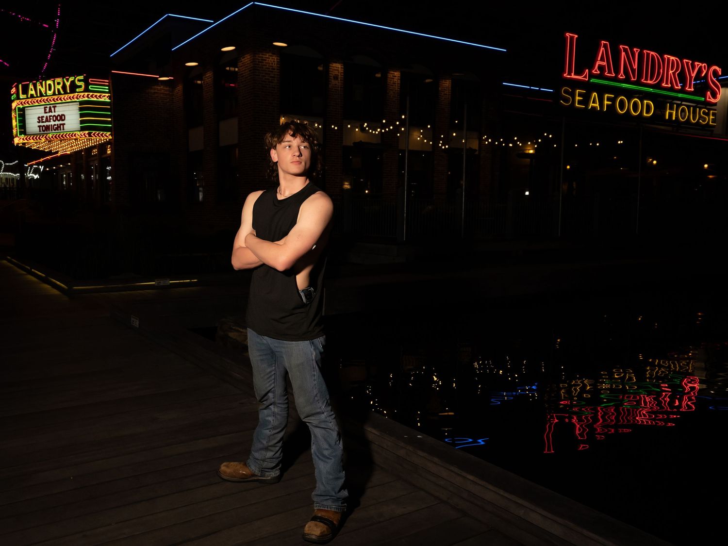 Person standing outside at night near illuminated restaurant signage.